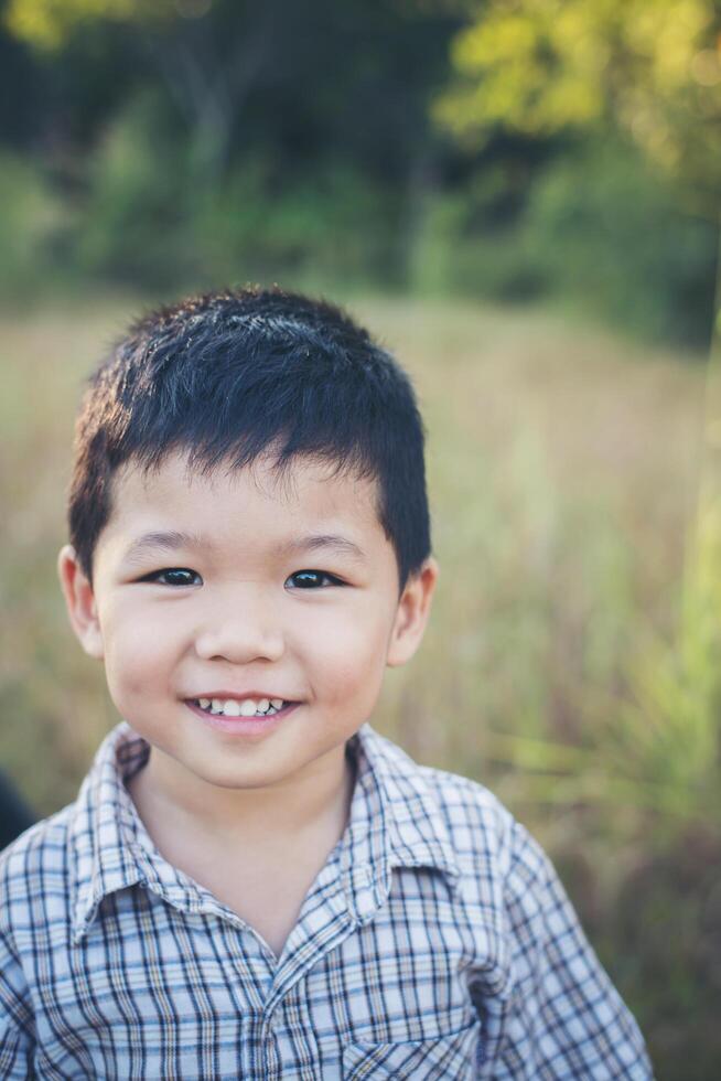 Nahaufnahme eines süßen asiatischen Jungen, der im Freien spielt und lächelt. foto