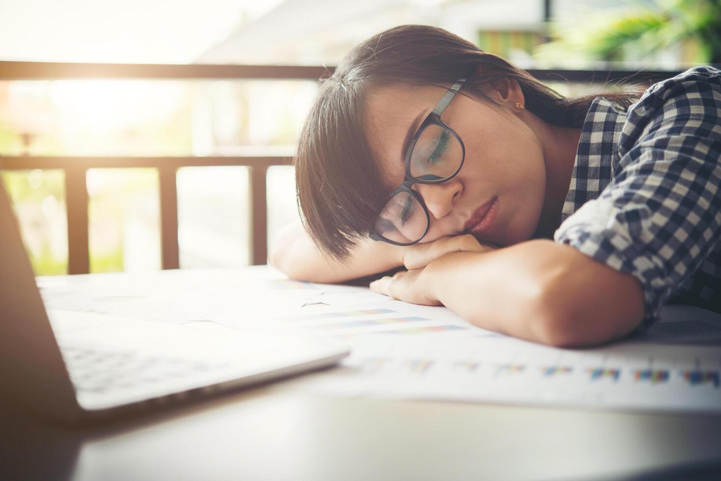 Müde Geschäftsfrau schläft auf einem Laptop, während sie an ihrem Arbeitsplatz arbeitet foto