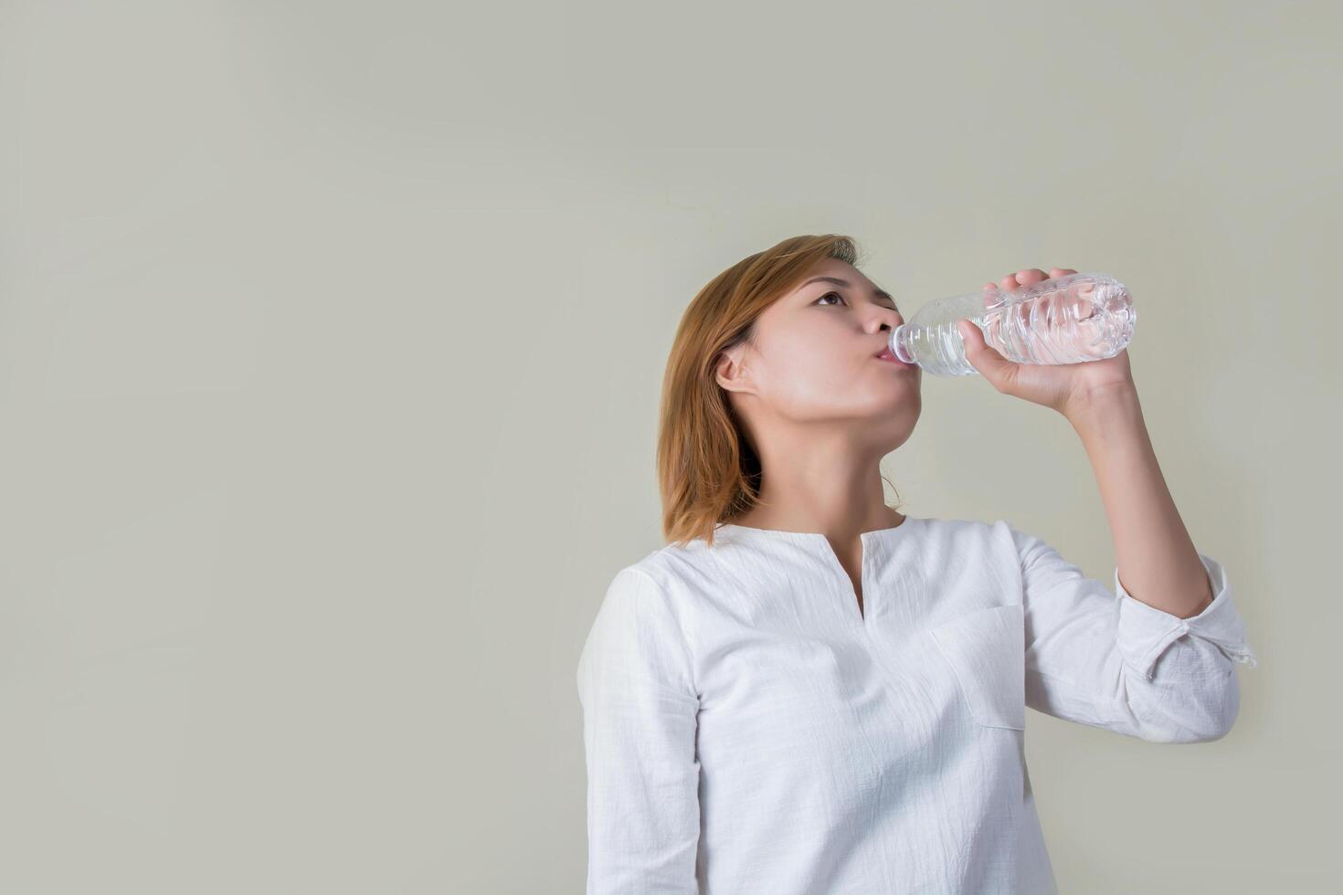 Junge gesunde Frau, die eine Flasche Wasser hält und in die Kamera lächelt foto