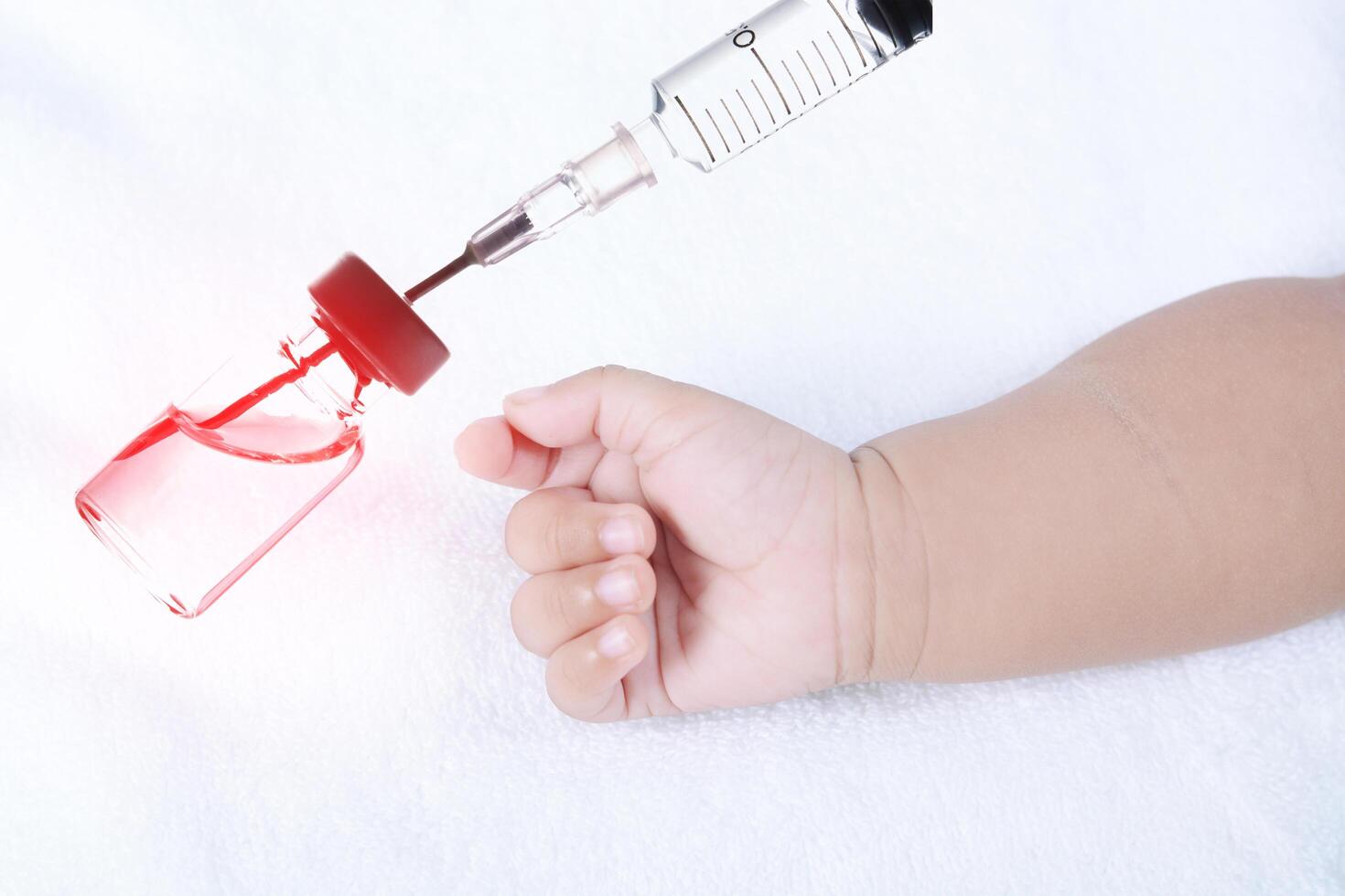 Säuglingsbabyhand mit medizinischer Insulinspritze foto