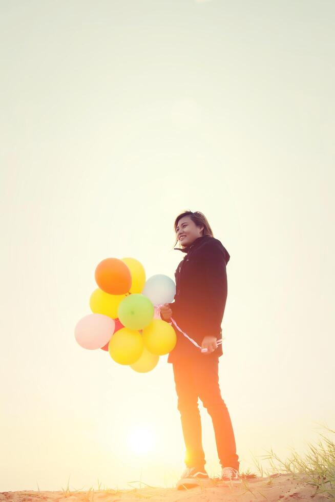 Hipster-Frau mit Luftballons im schwarzen Mantel im Winter foto