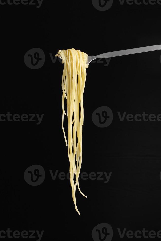 gekochte Spaghetti in Gabel auf schwarzem Hintergrund foto