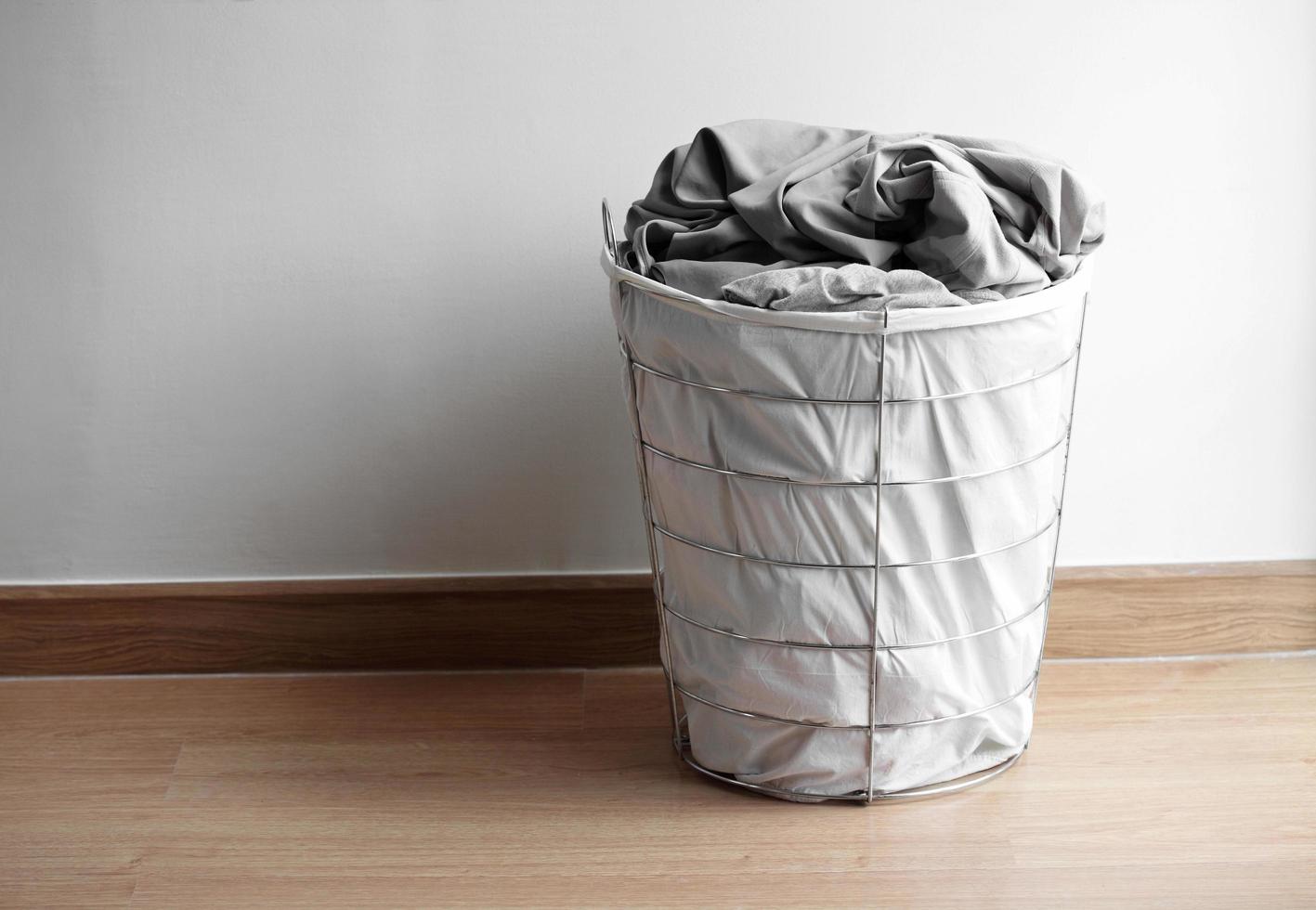 moderner Korb mit schmutziger Wäsche auf dem Boden foto