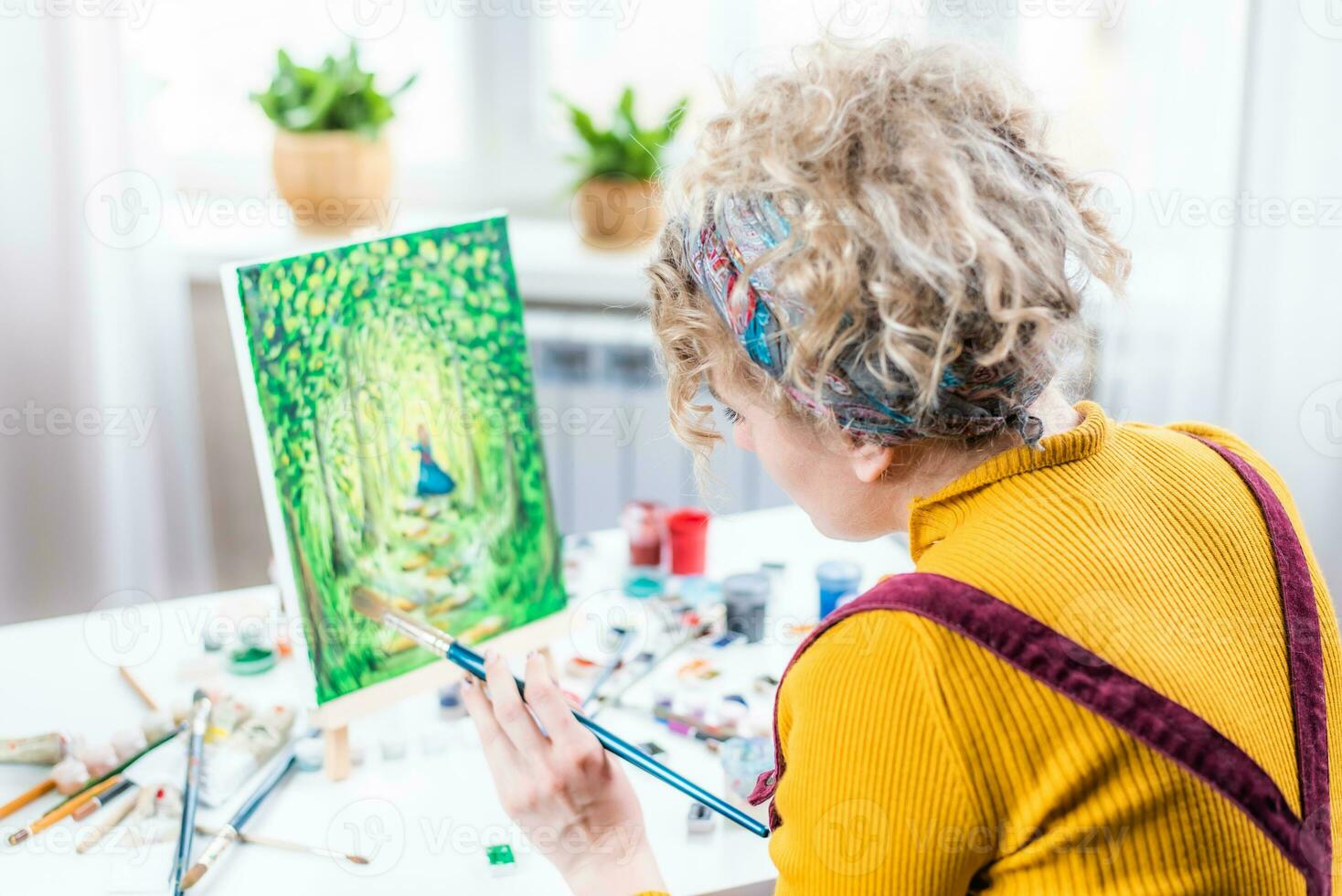 lockig blond Frau Gemälde ein Bild durch das Fenster foto