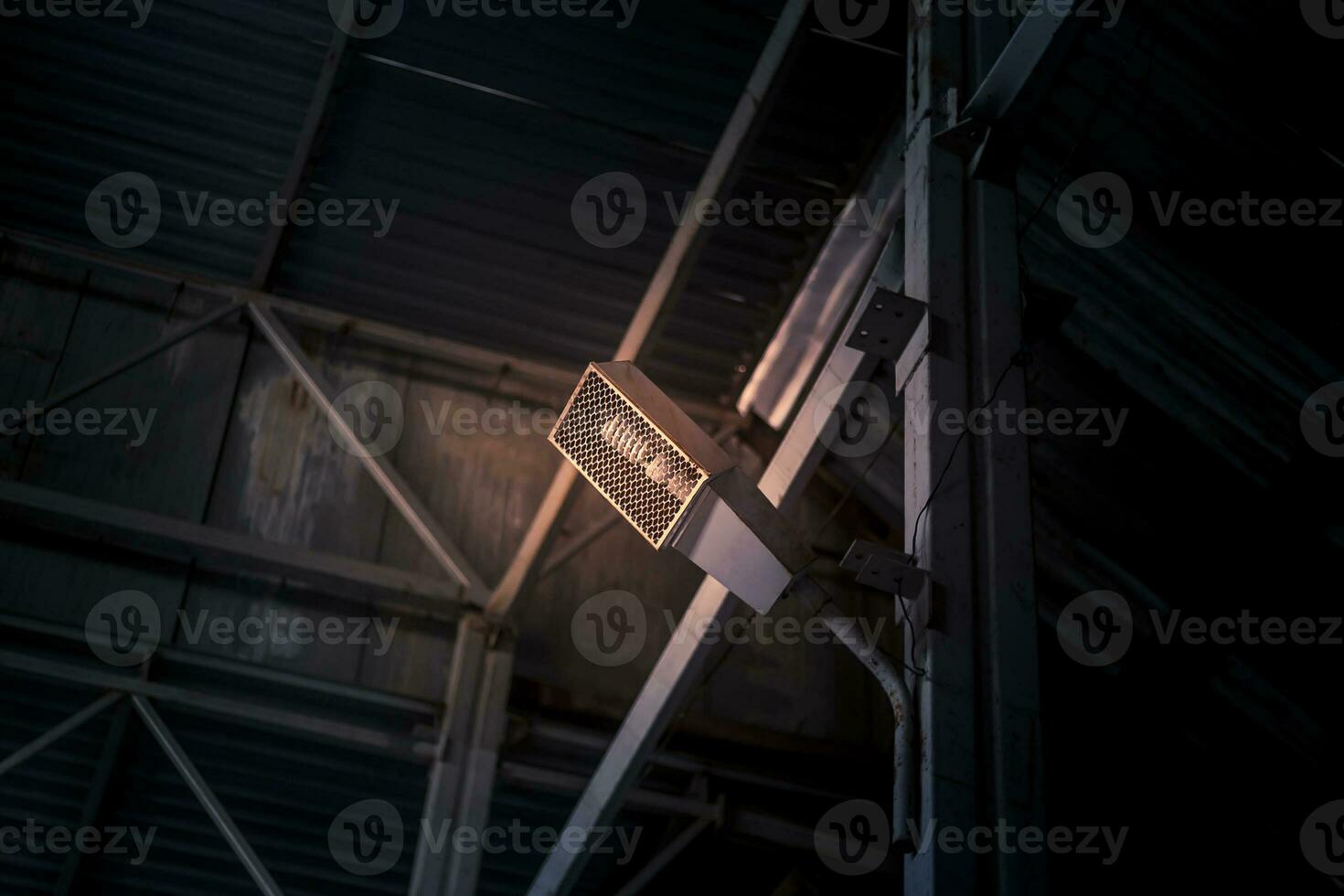 industriell Licht Birne im ein schützend Draht Käfig, montiert beim das Metall Mauer foto