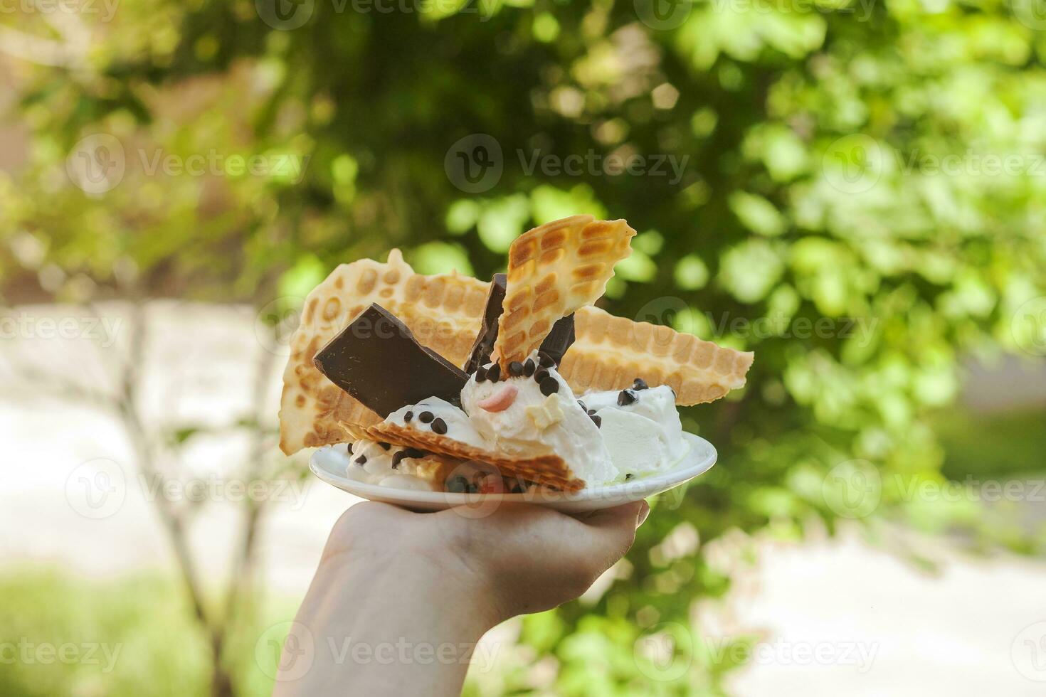 jung Frau halten köstlich Eis Sahne mit Waffel während ein Picknick beim Natur. Sommer- Essen Konzept. jung Erwachsene Essen lecker Eis Sahne mit ein Stock auf ein hell Sommer- Tag. foto