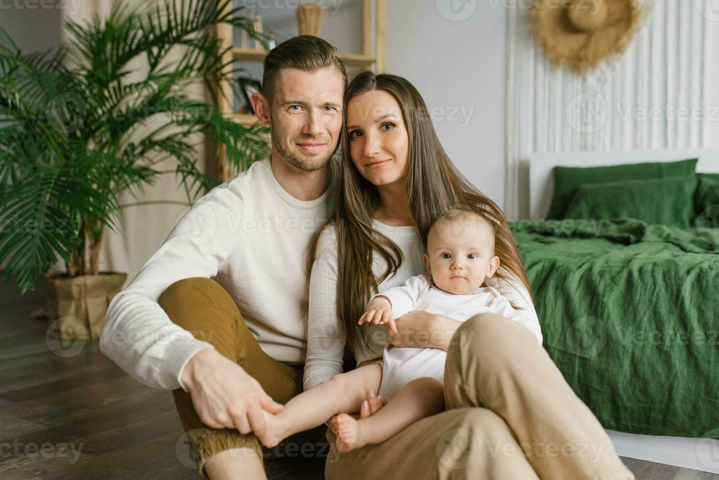 Porträt von Mutter, Papa und sechs Monate alt Baby Sohn im ihr Waffen Ausgaben Zeit zusammen im ihr gemütlich Zuhause foto