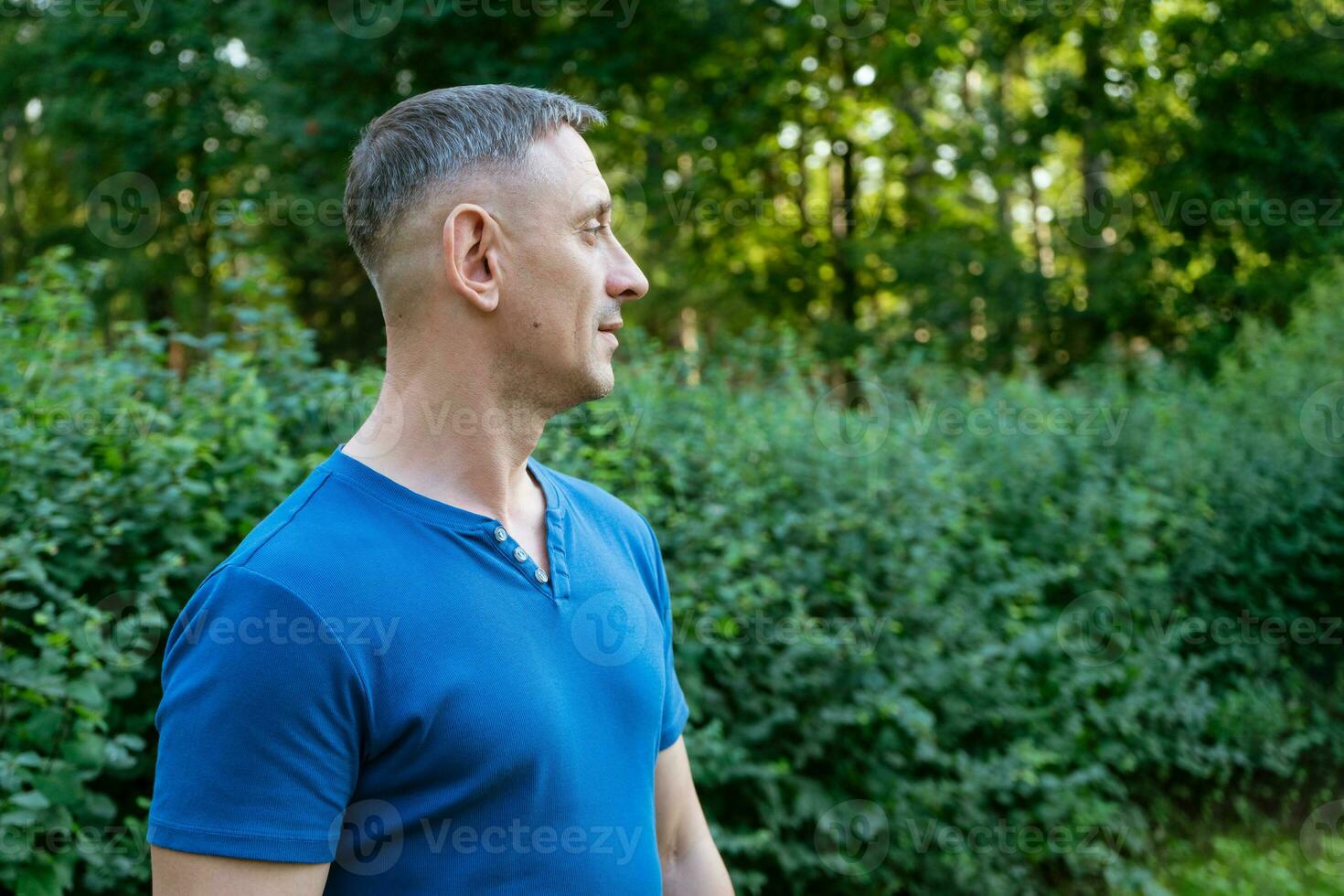 gut aussehend Porträt von ein Mann im ein Blau T-Shirt auf ein Park foto