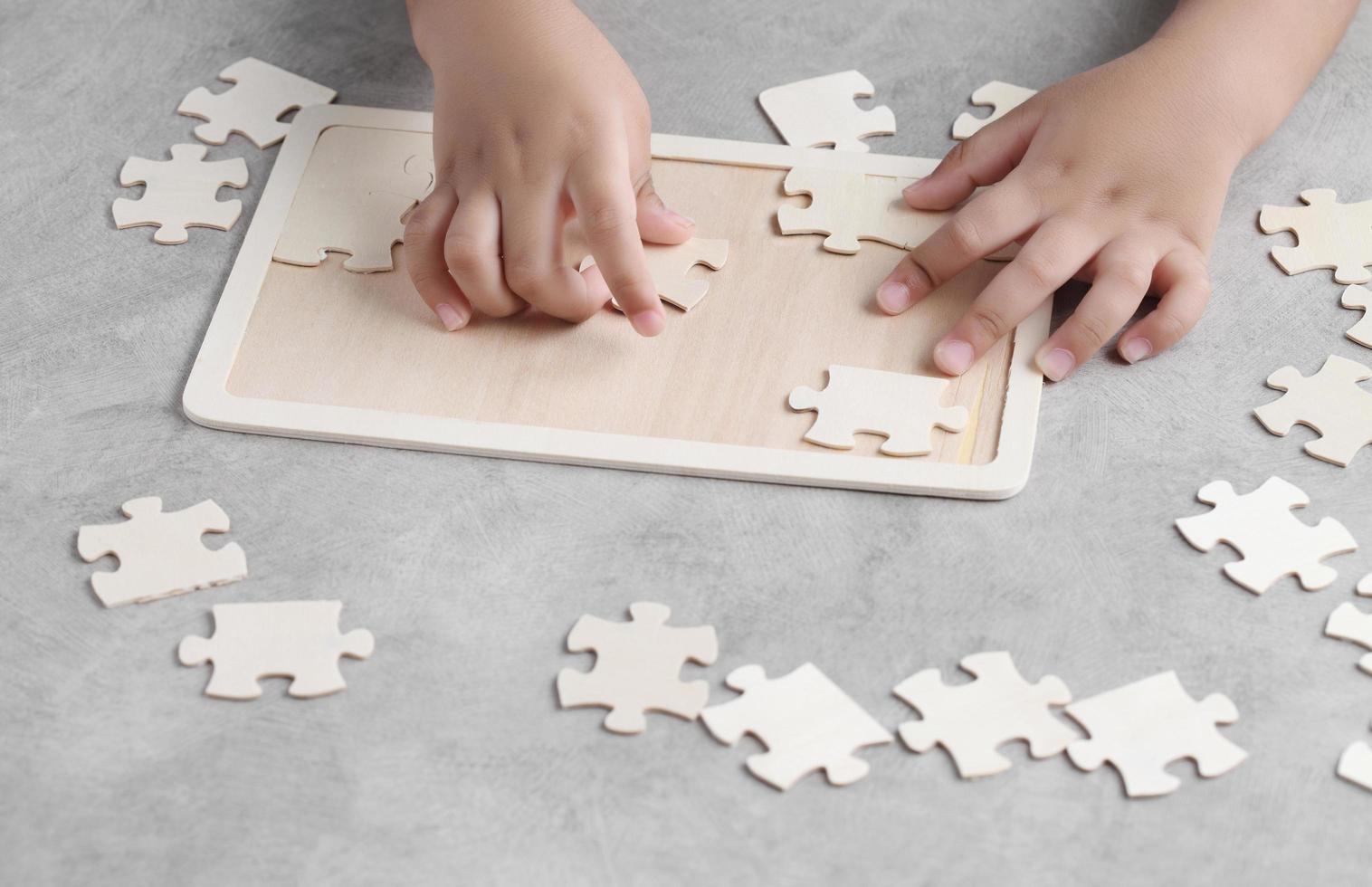 asiatischer kleiner Junge, der hölzernes Puzzlespiel spielt foto