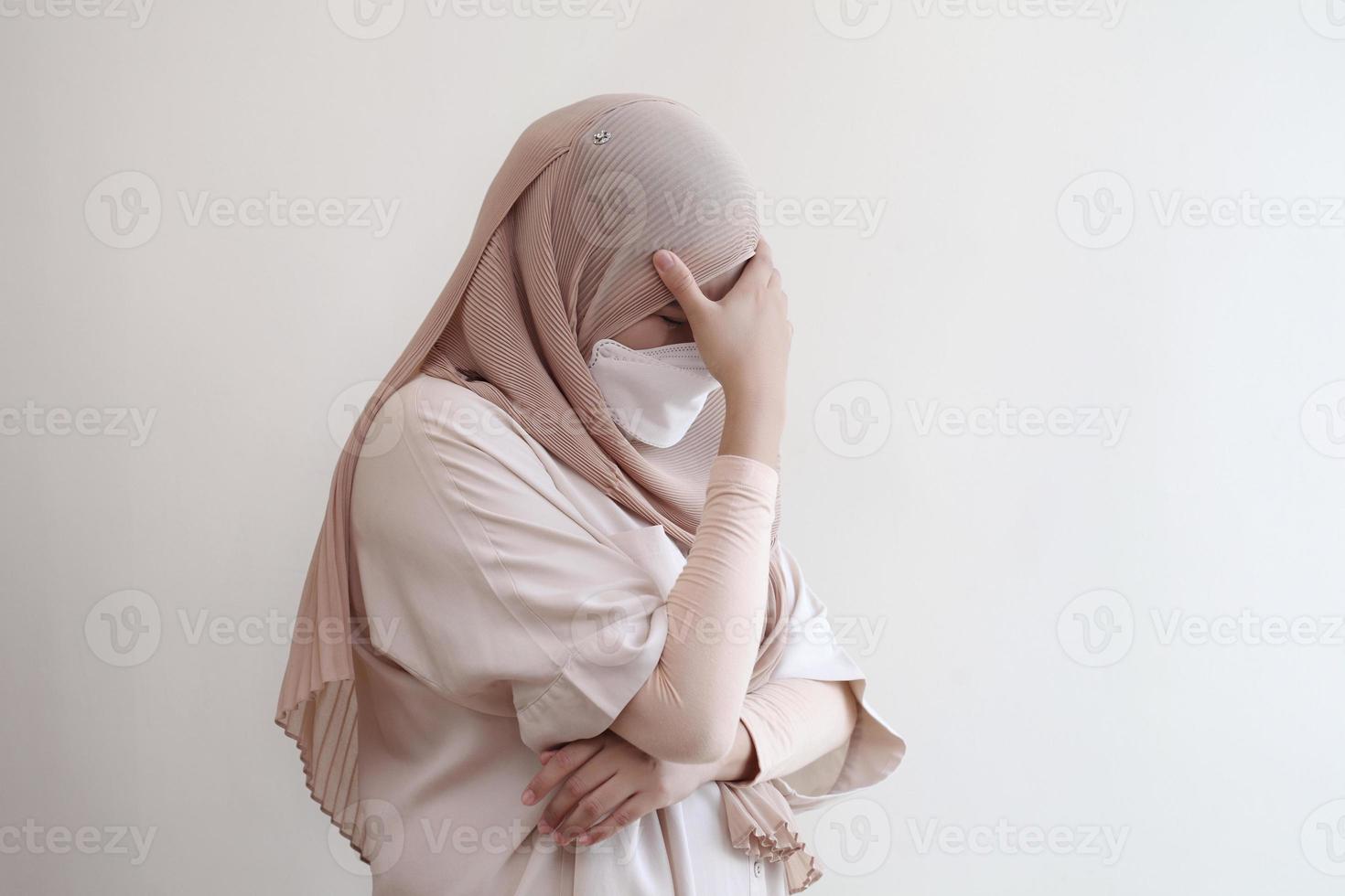 muslimische Frau mit Maske, die sich auf pastellfarbenem Hintergrund krank fühlt. foto