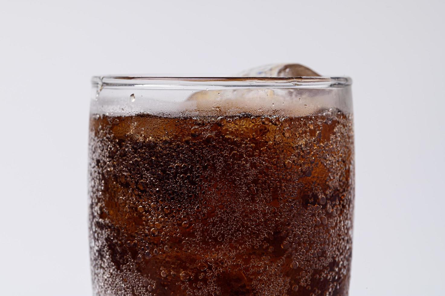 Cola im Glas mit klaren Eiswürfeln auf weißem Hintergrund foto