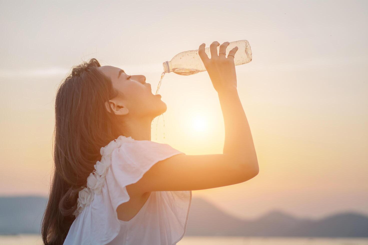 schöne frau, die morgens trinkwasser aus der flasche steht foto