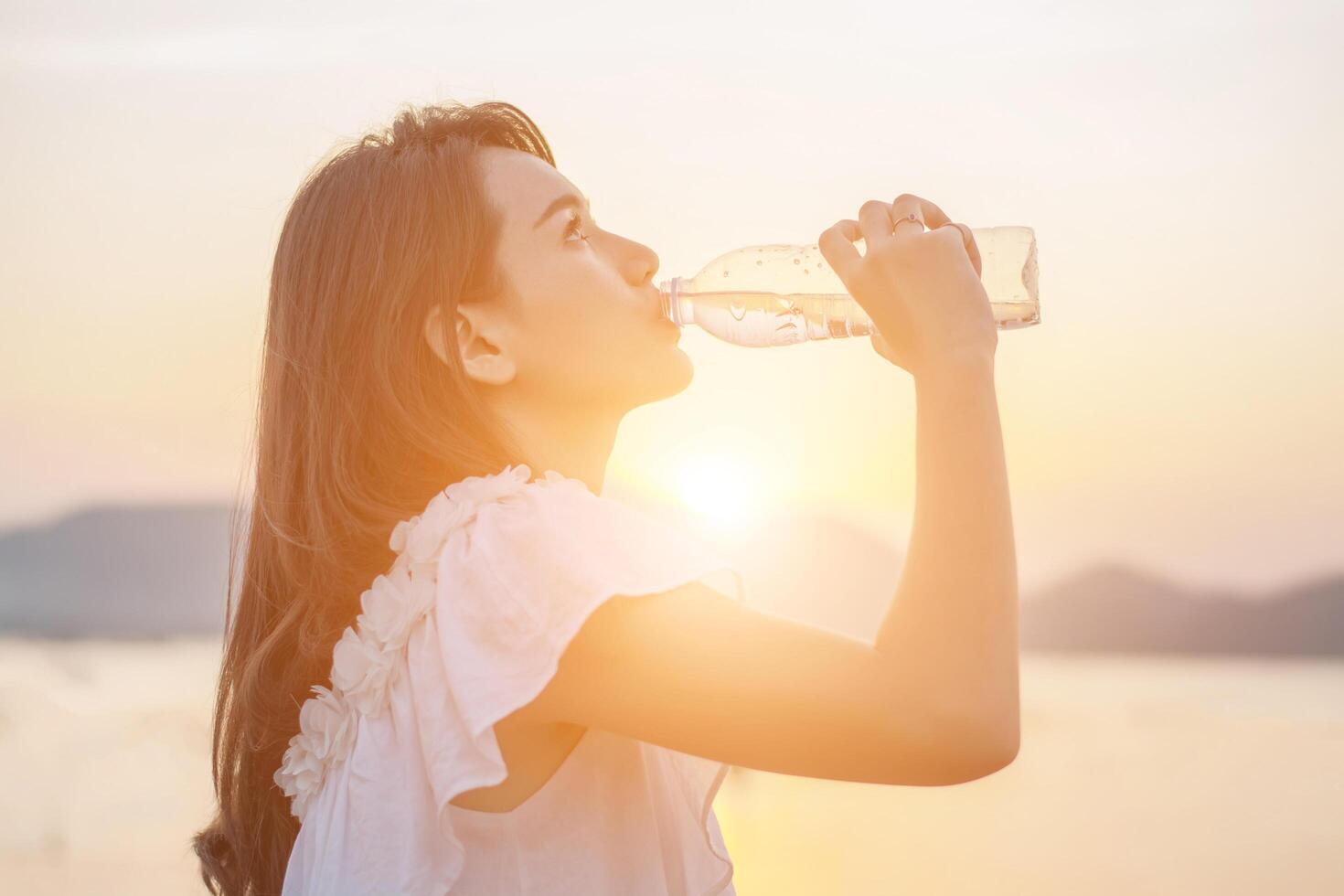 schöne junge Frau trinkt Wasser mit Sonnenaufgang am Morgen foto