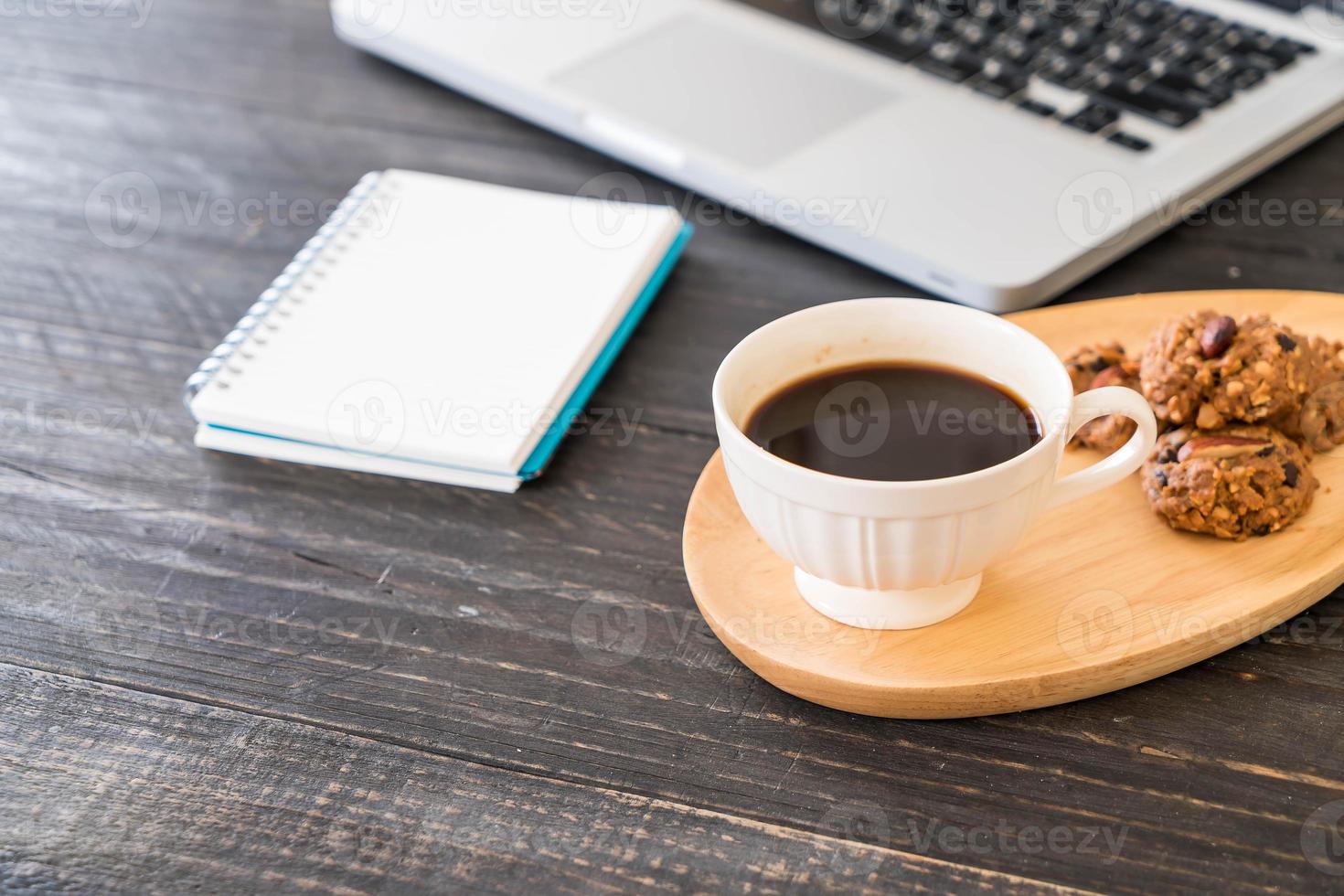 schwarzer Kaffee und Kekse mit Laptop und Notebook auf dem Tisch foto