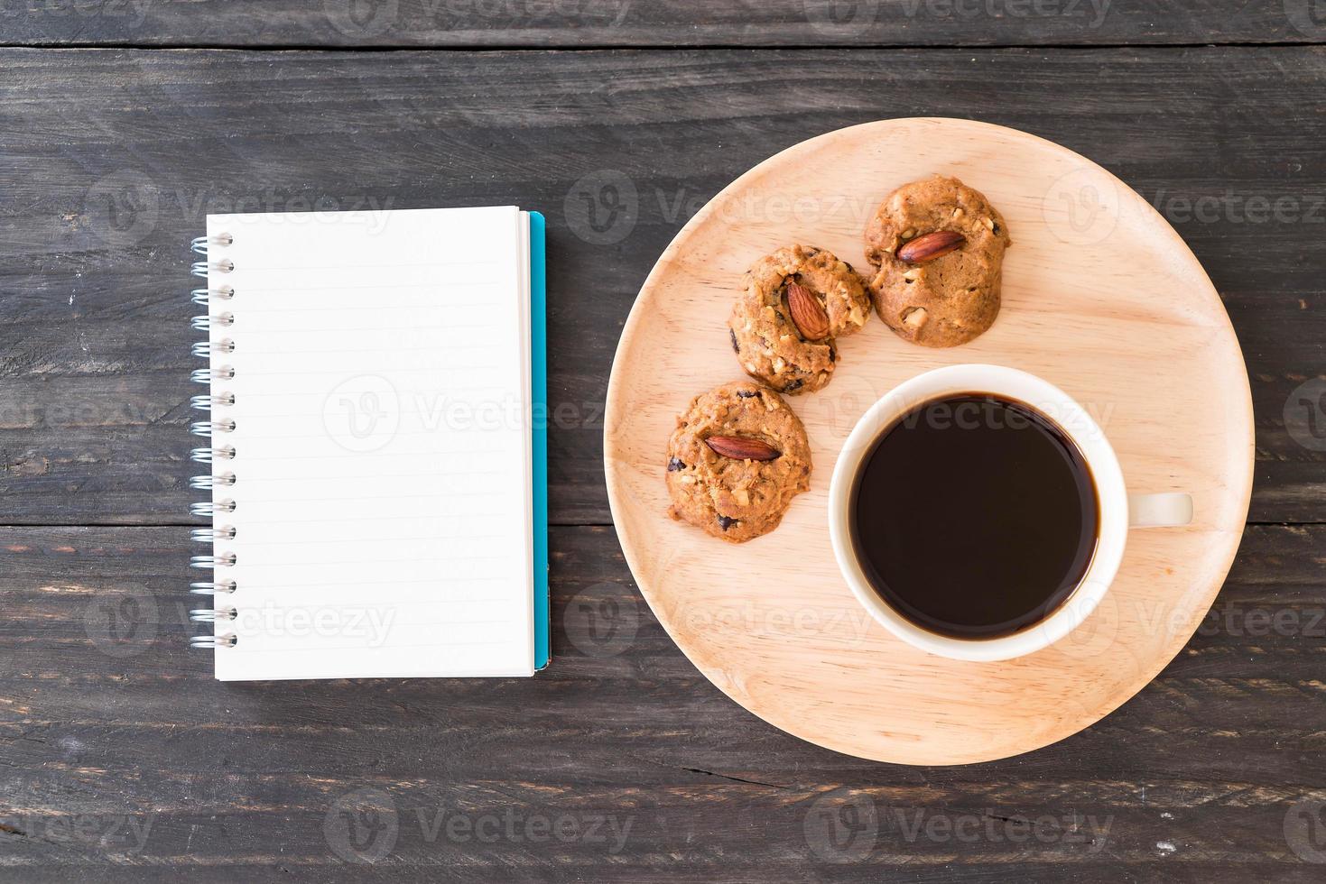 schwarzer Kaffee und Kekse mit Notizbuch auf dem Tisch foto