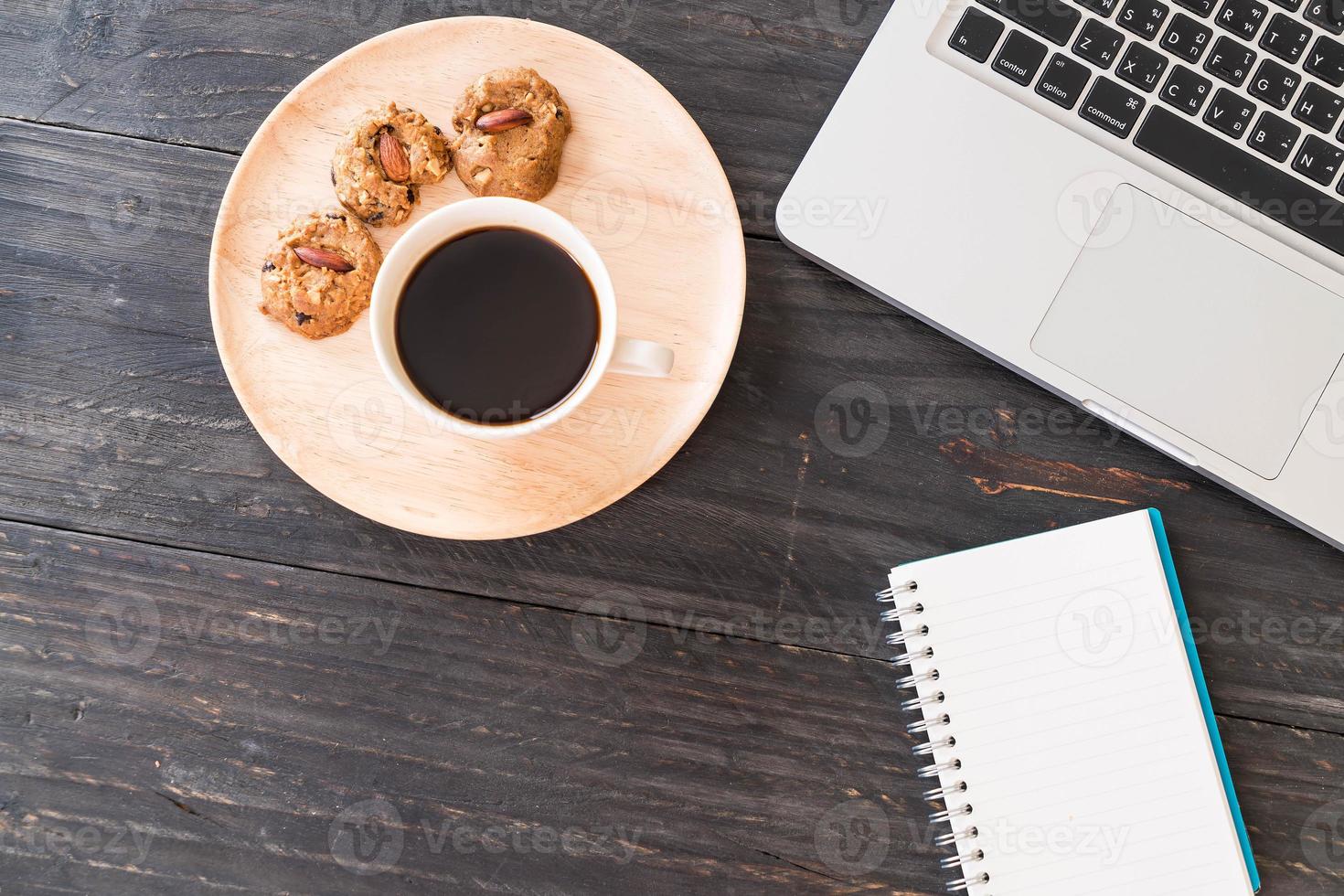 schwarzer Kaffee und Kekse mit Laptop und Notebook auf dem Tisch foto