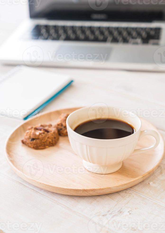 schwarzer Kaffee und Kekse mit Laptop und Notebook auf dem Tisch foto