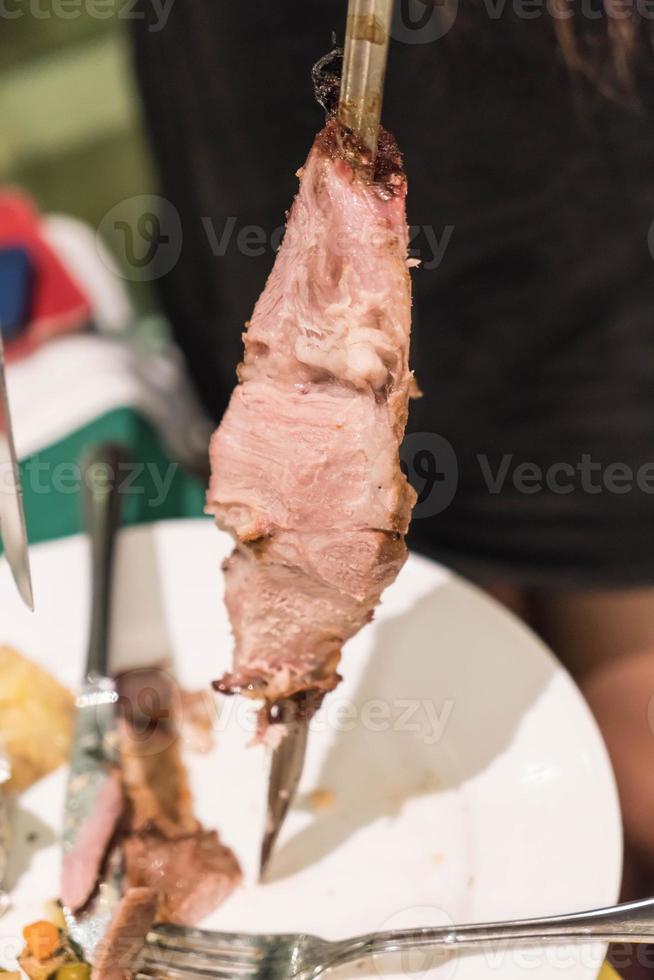 Schneiden von Steak nach brasilianischer Art auf Teller foto