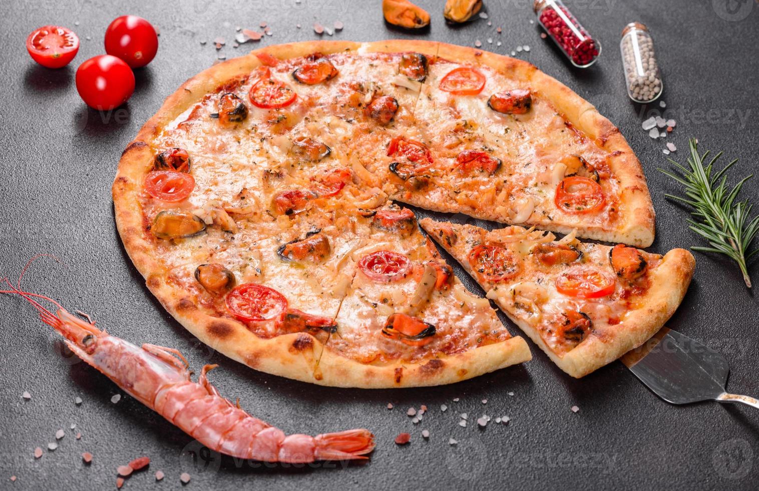 leckere Pizzascheiben mit Meeresfrüchten und Tomaten auf Betonuntergrund foto