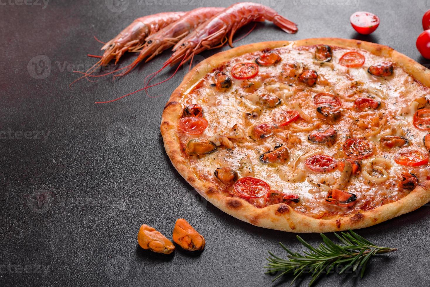 leckere Pizzascheiben mit Meeresfrüchten und Tomaten auf Betonuntergrund foto