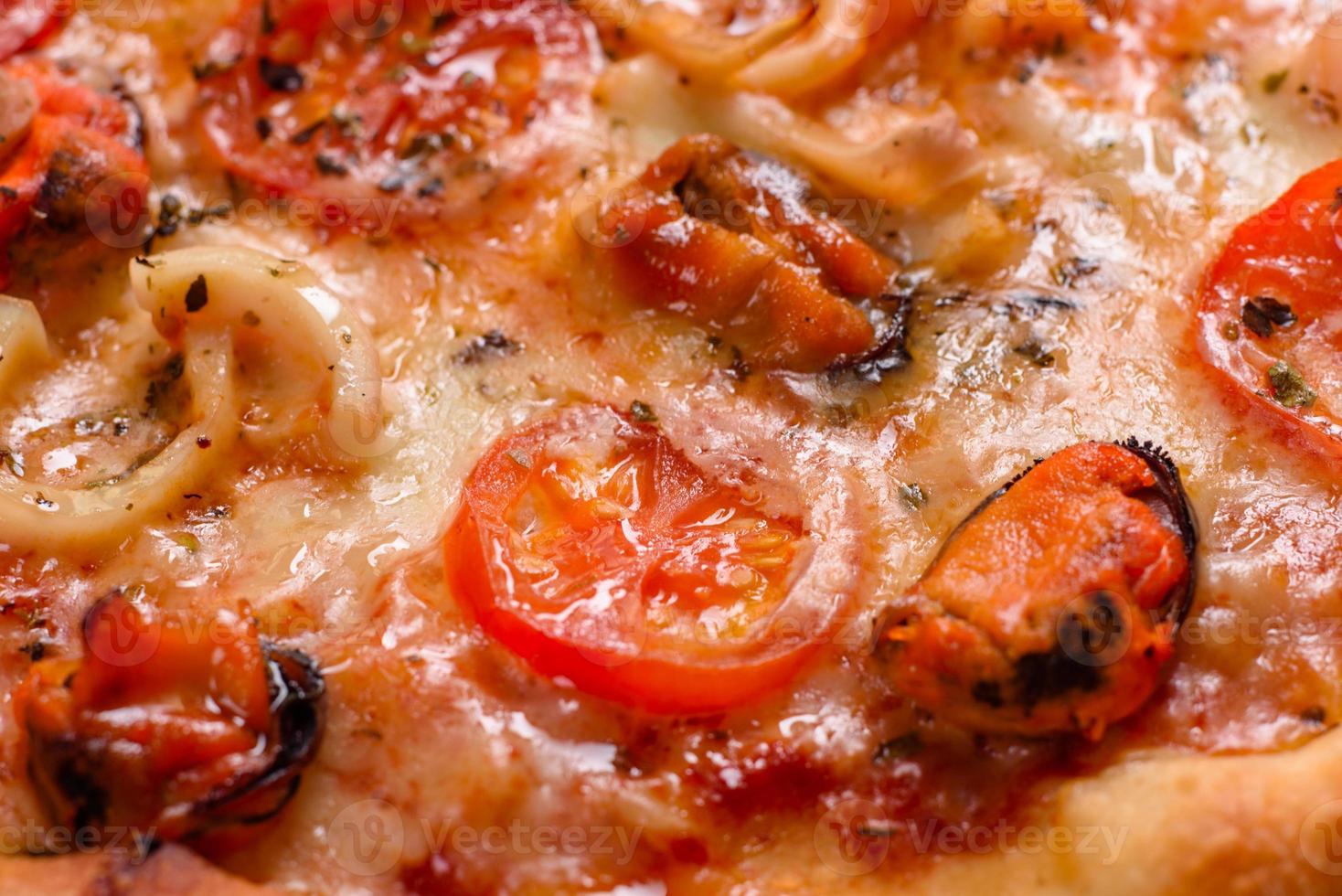 leckere Pizzascheiben mit Meeresfrüchten und Tomaten auf Betonuntergrund foto