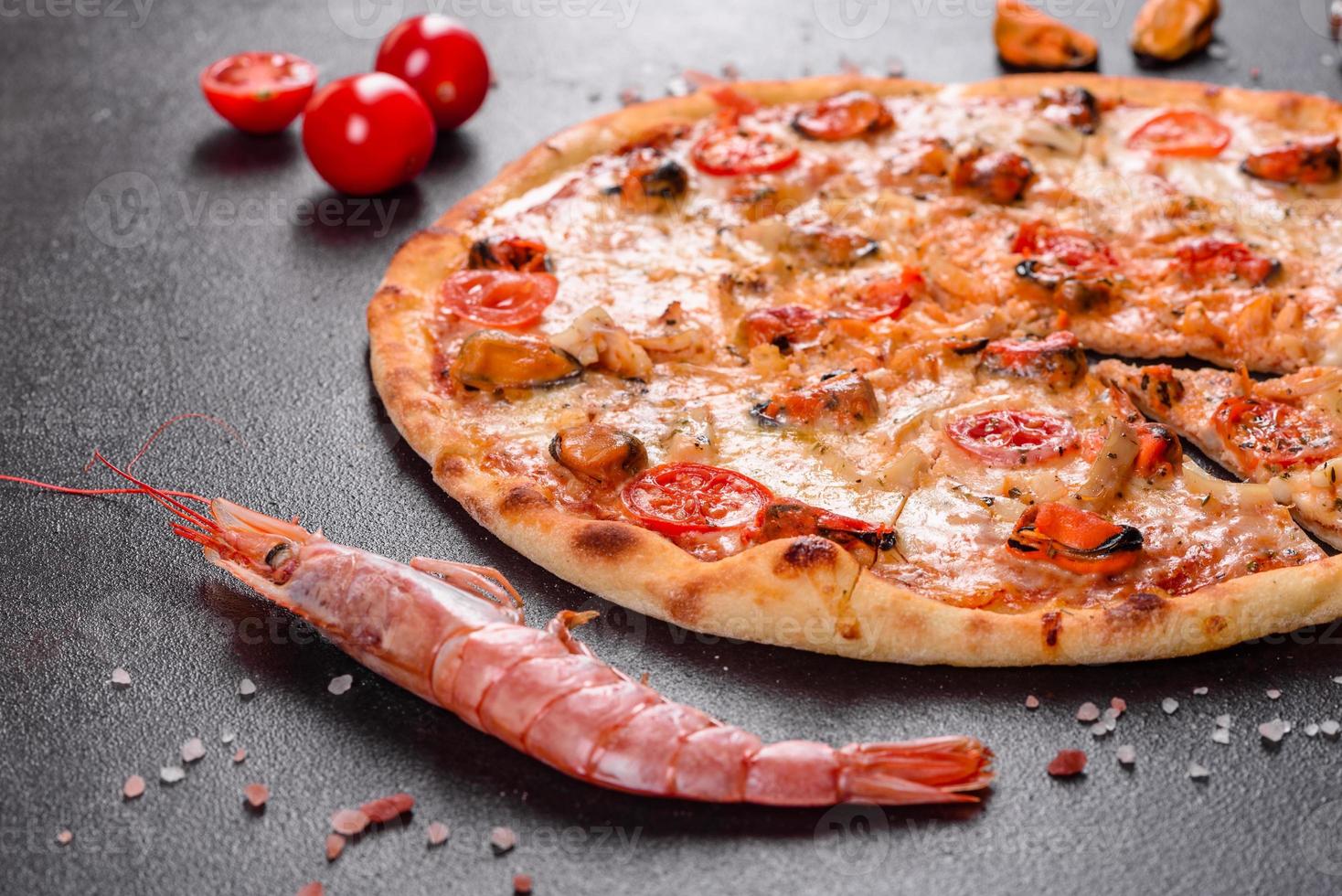 leckere Pizzascheiben mit Meeresfrüchten und Tomaten auf Betonuntergrund foto