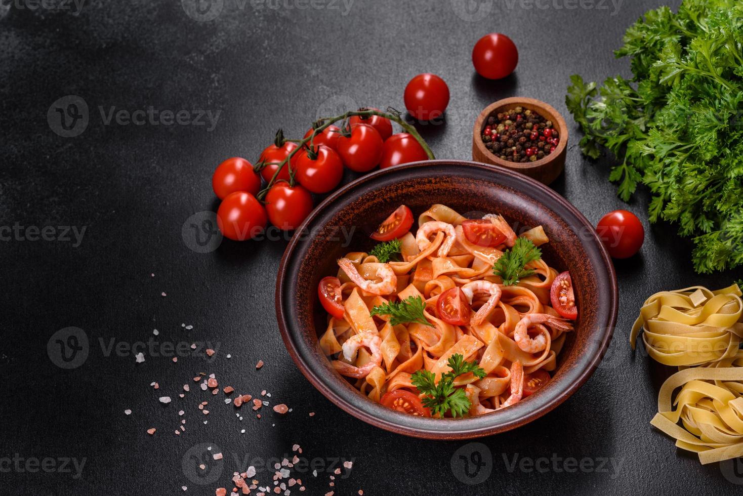 Fettuccine-Nudeln mit Garnelen, Kirschtomaten, Sauce, Gewürzen und Kräutern foto