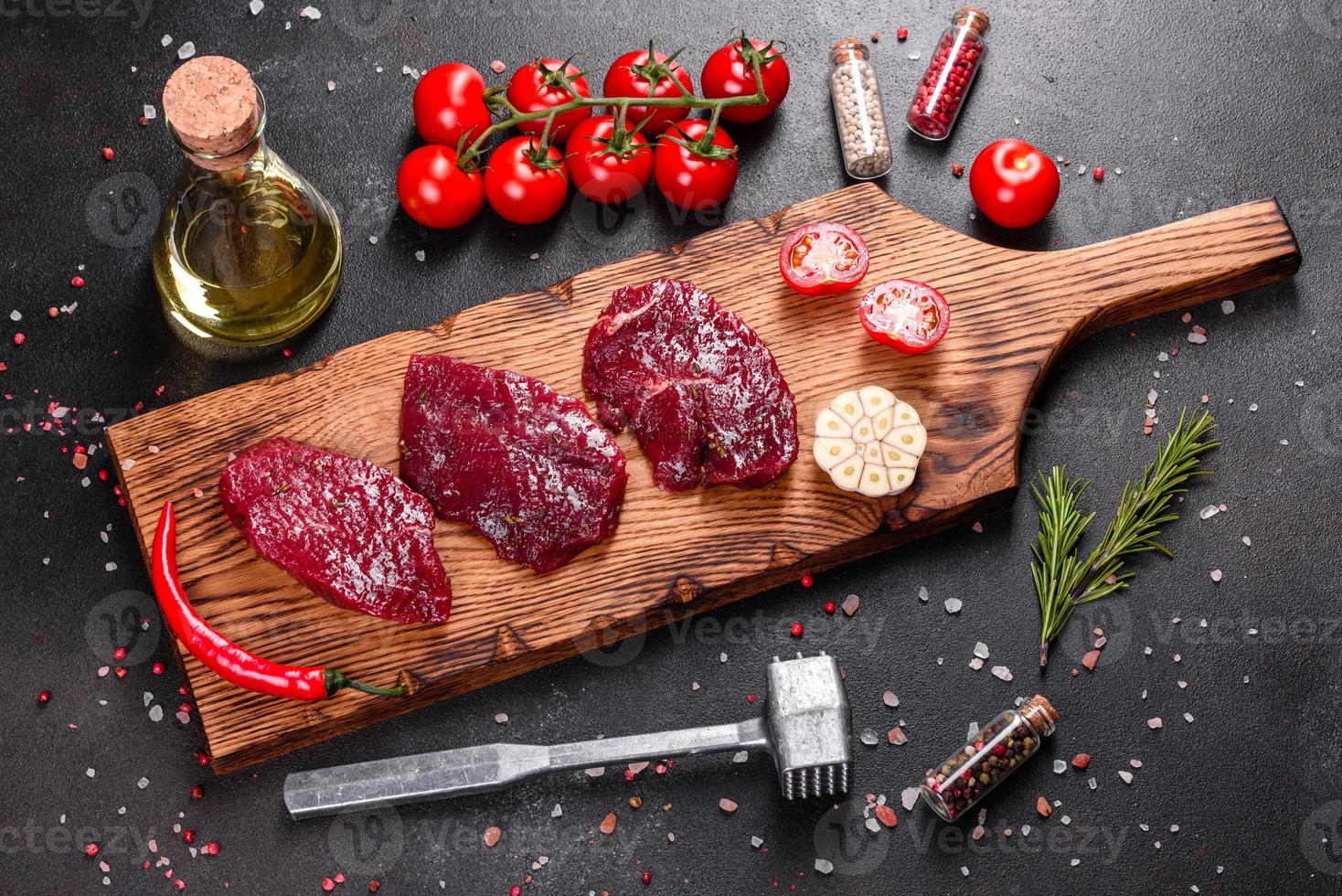 frisches rohes Rindersteak Mignon, mit Salz, Pfefferkörner, Thymian, Tomaten foto