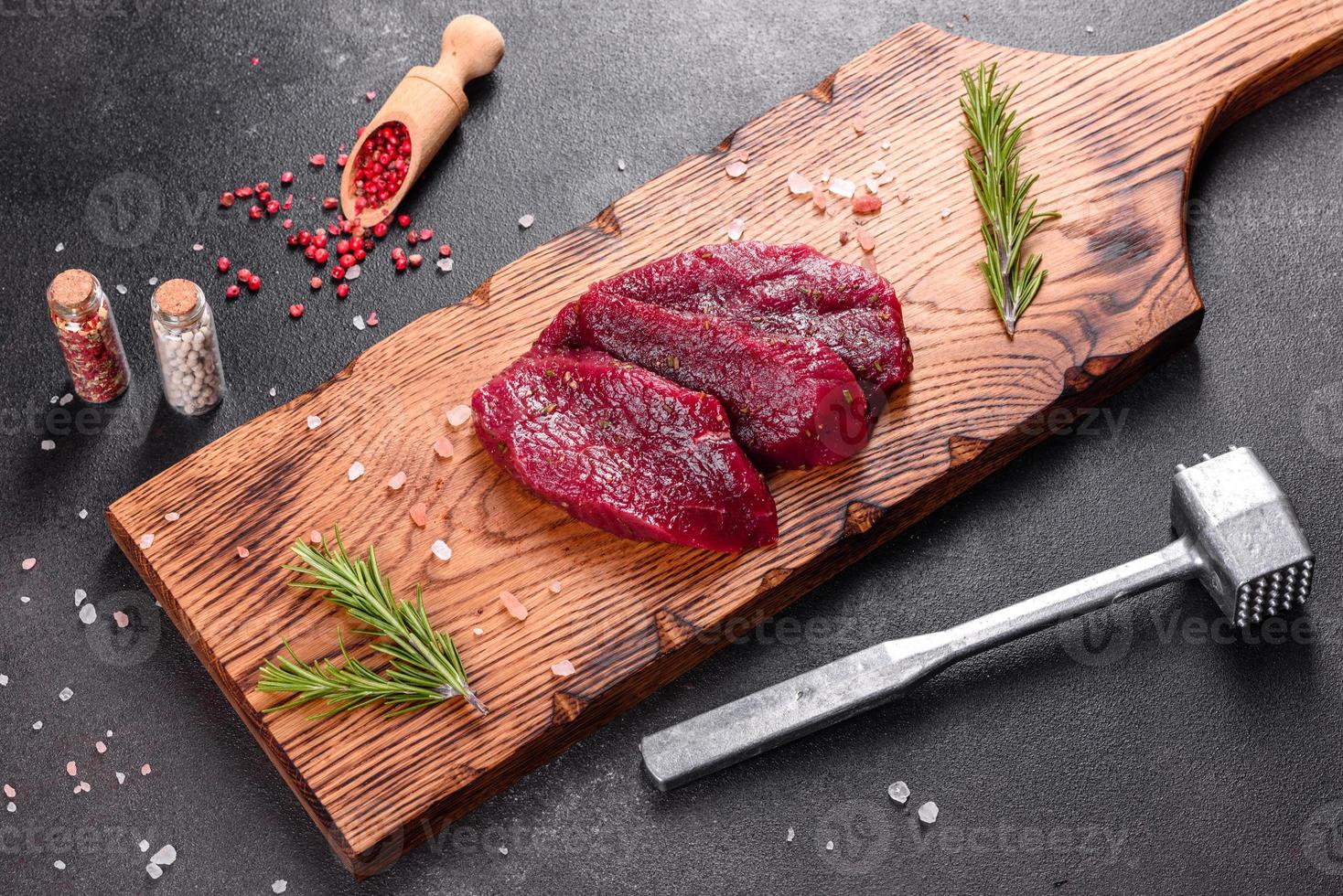 frisches rohes Rindersteak Mignon, mit Salz, Pfefferkörner, Thymian, Tomaten foto