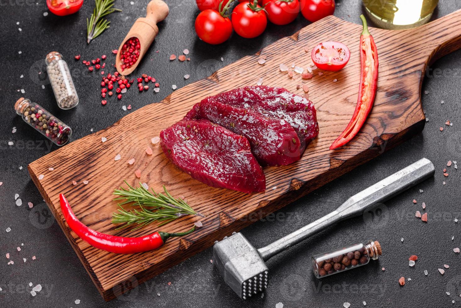 frisches rohes Rindersteak Mignon, mit Salz, Pfefferkörner, Thymian, Tomaten foto