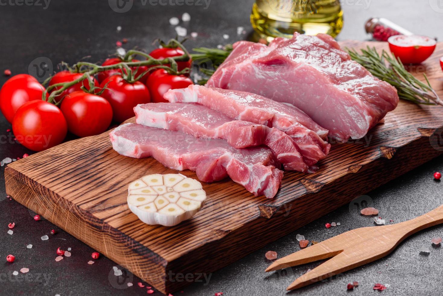 frische Stücke Schweinefleisch kochfertig auf dunklem Hintergrund in der Küche foto