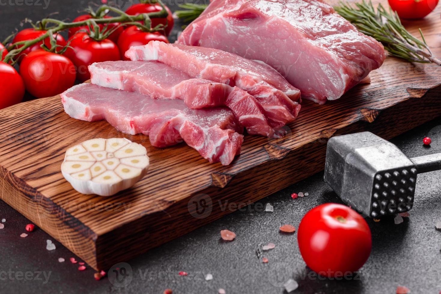 frische Stücke Schweinefleisch kochfertig auf dunklem Hintergrund in der Küche foto