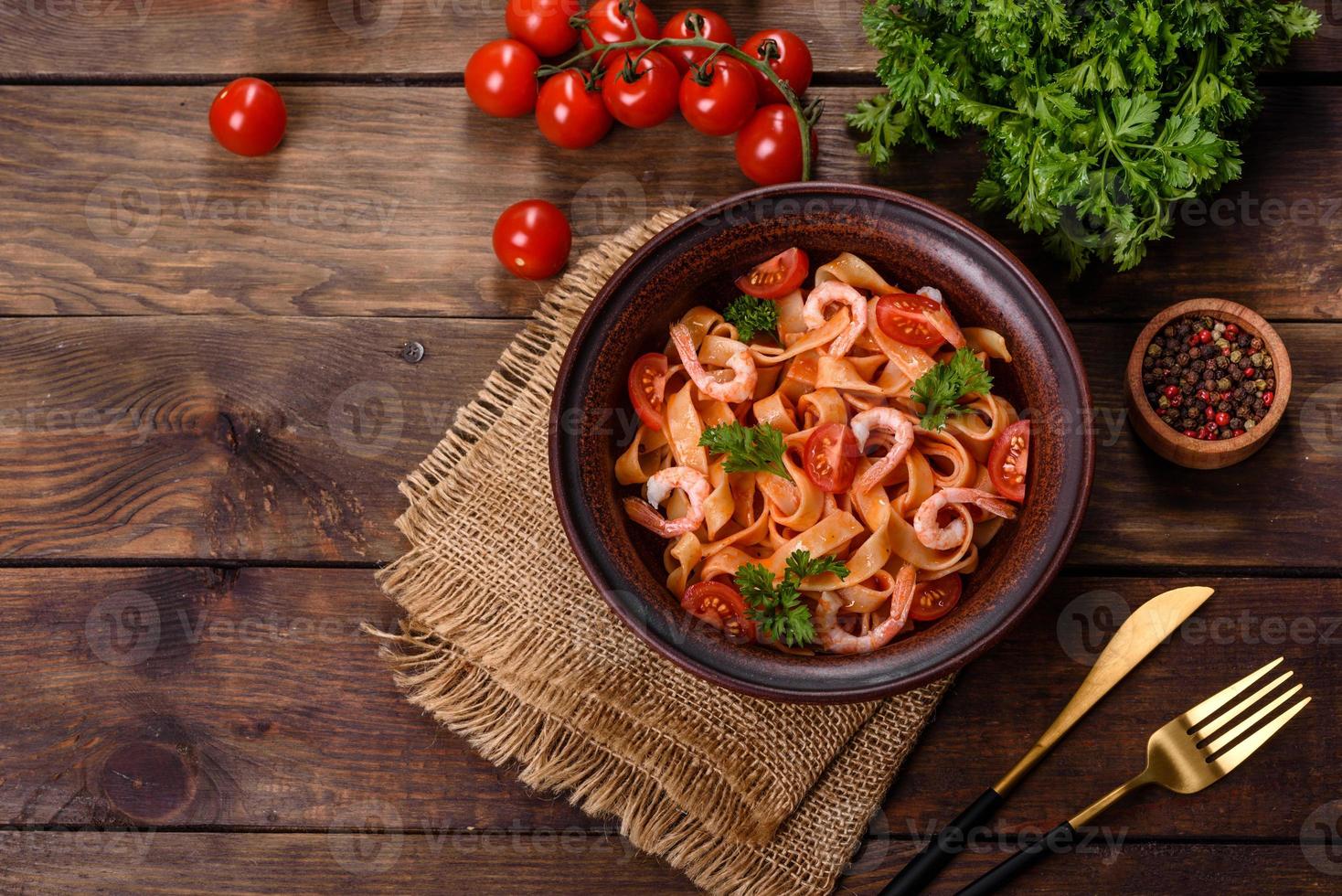 Fettuccine-Nudeln mit Garnelen, Kirschtomaten, Sauce, Gewürzen und Kräutern foto