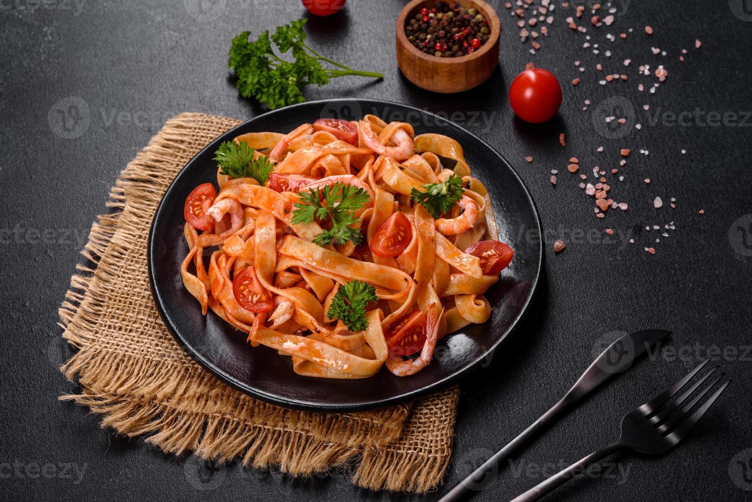 Fettuccine-Nudeln mit Garnelen, Kirschtomaten, Sauce, Gewürzen und Kräutern foto