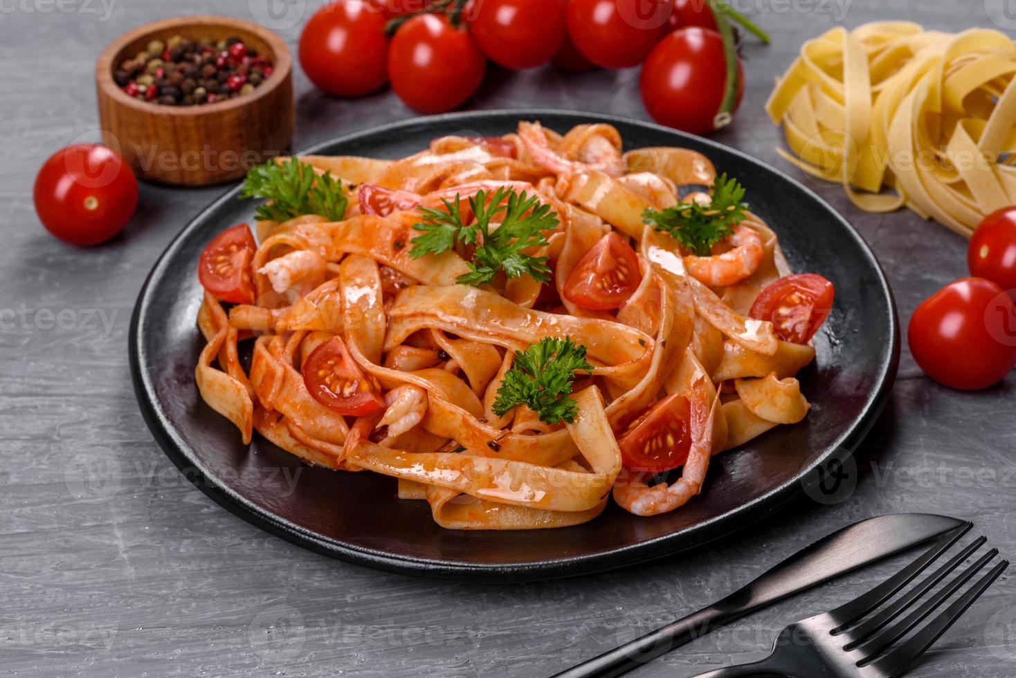 Fettuccine-Nudeln mit Garnelen, Kirschtomaten, Sauce, Gewürzen und Kräutern foto