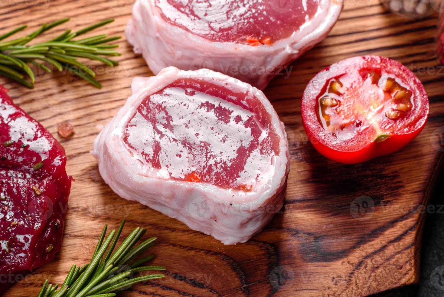 frisches rohes Rindersteak Mignon, mit Salz, Pfefferkörner, Thymian, Tomaten foto