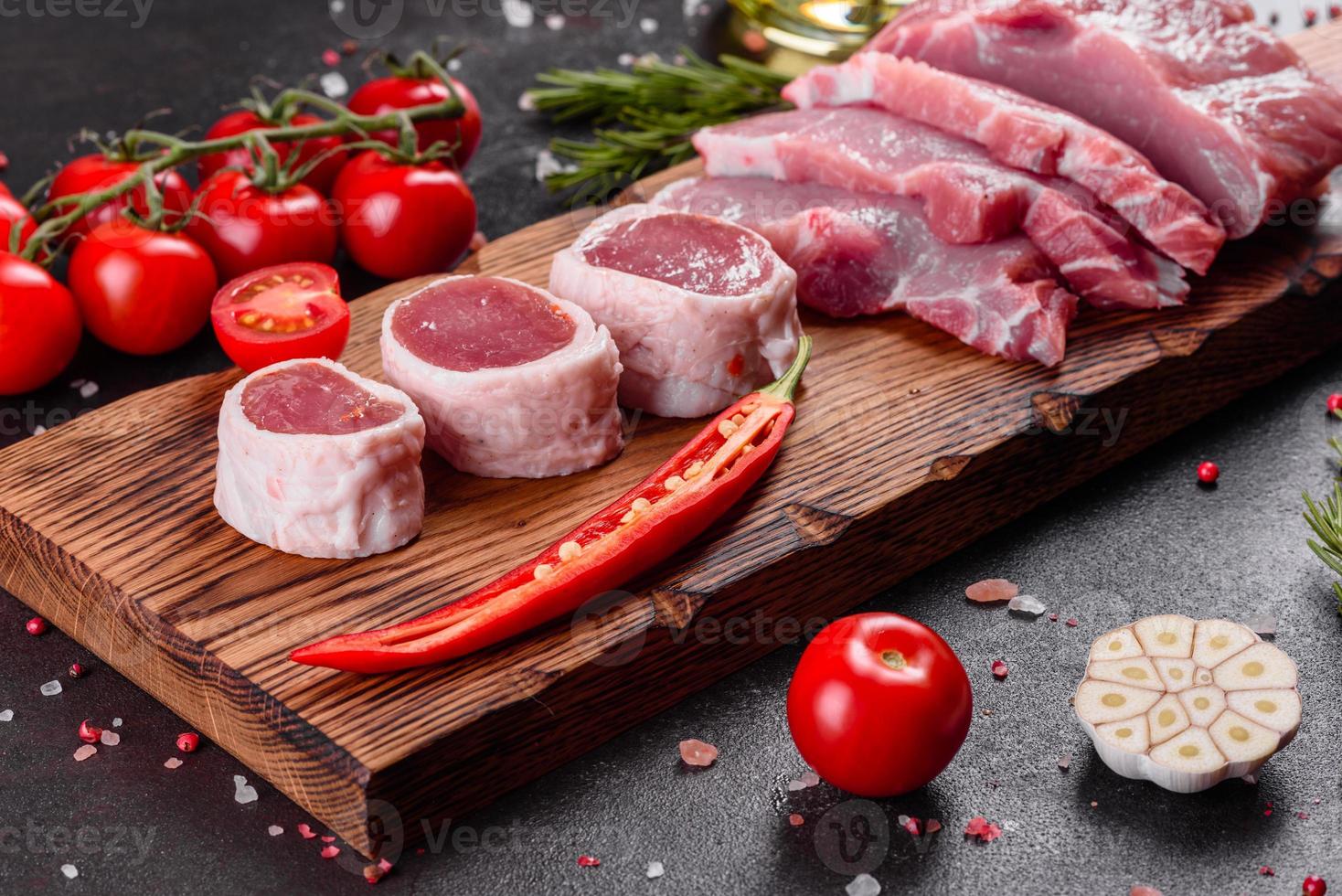 frische Stücke Schweinefleisch kochfertig auf dunklem Hintergrund foto