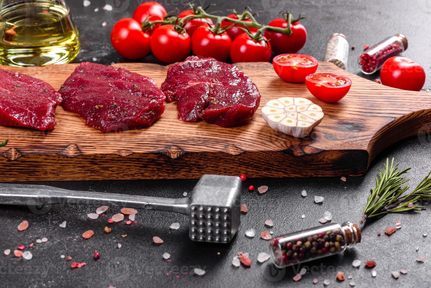 frisches rohes Rindersteak Mignon, mit Salz, Pfefferkörner, Thymian, Tomaten foto