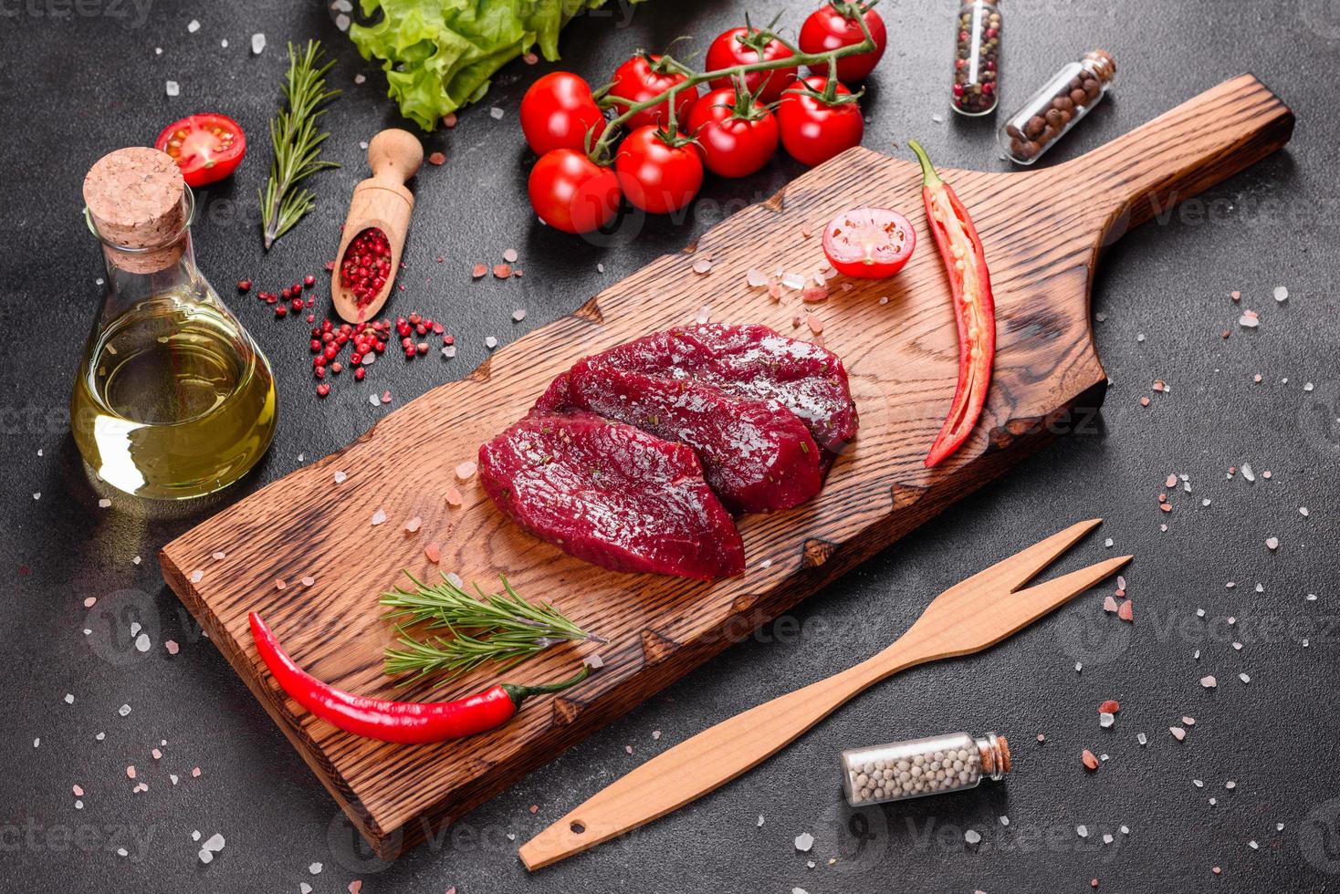 frisches rohes Rindersteak Mignon, mit Salz, Pfefferkörner, Thymian, Tomaten foto