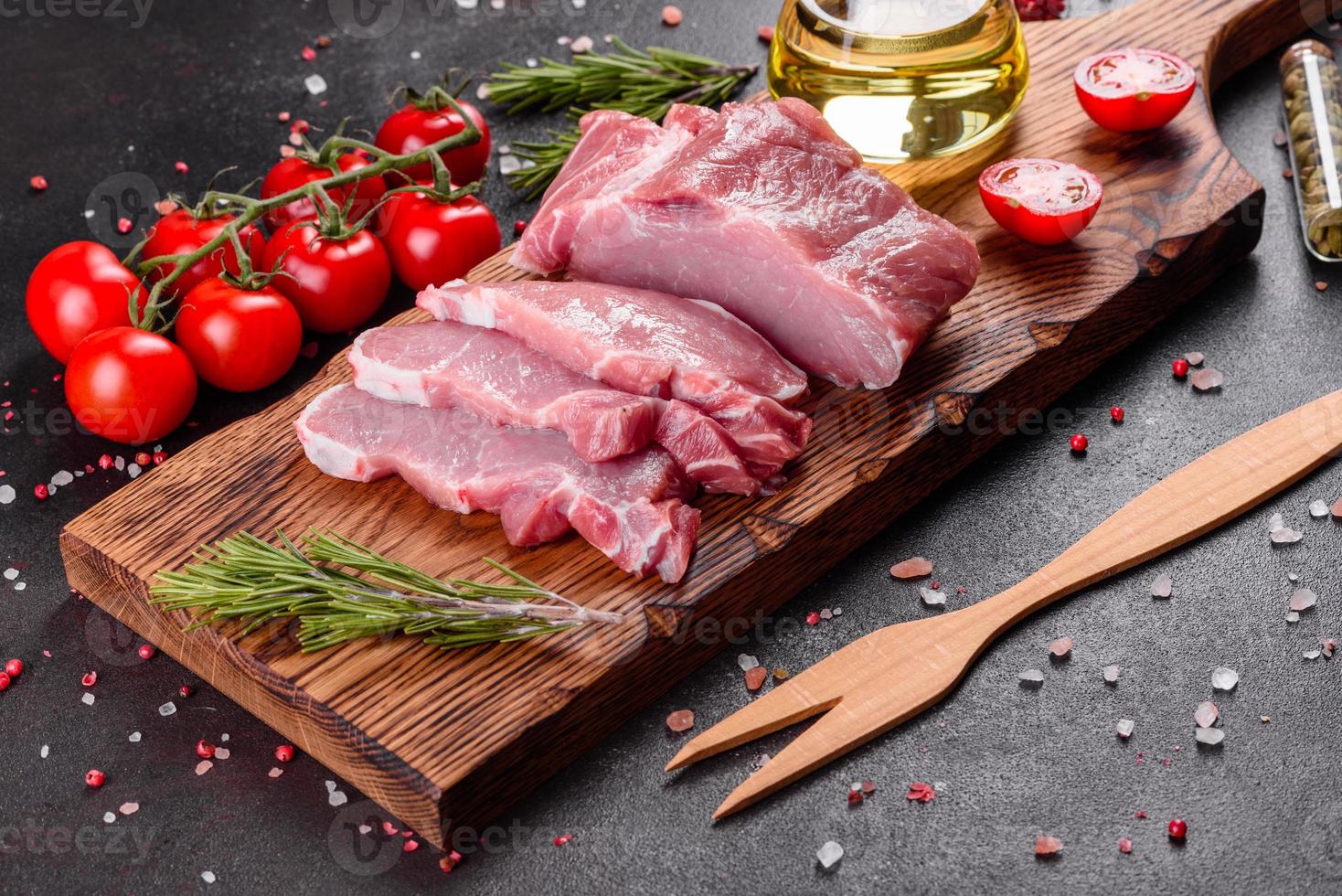 frische Stücke Schweinefleisch kochfertig auf dunklem Hintergrund in der Küche foto