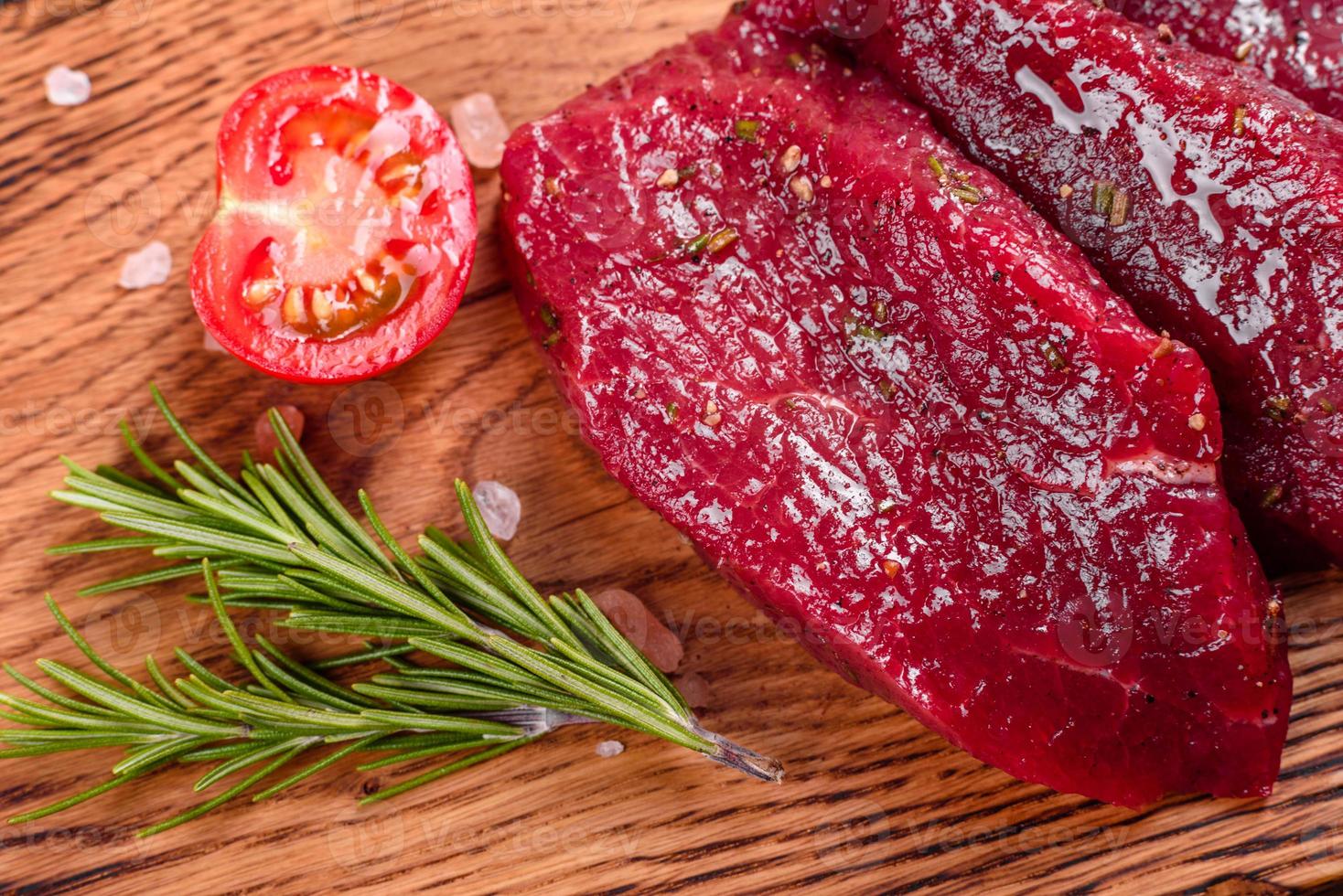 frisches rohes Rindersteak Mignon, mit Salz, Pfefferkörner, Thymian, Tomaten foto