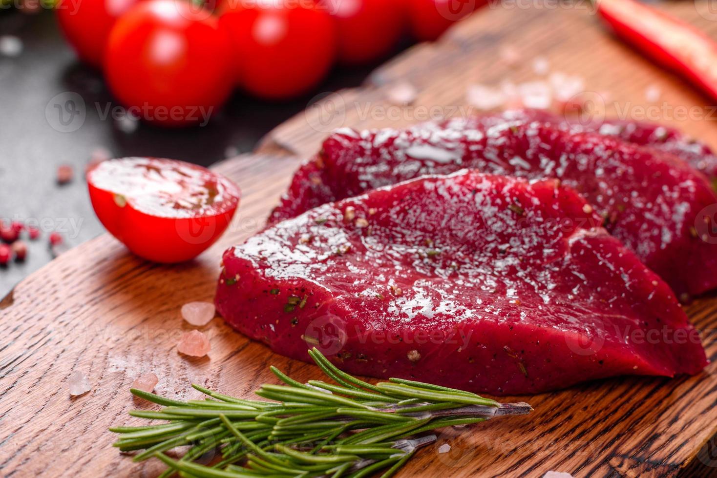 frisches rohes Rindersteak Mignon, mit Salz, Pfefferkörner, Thymian, Tomaten foto