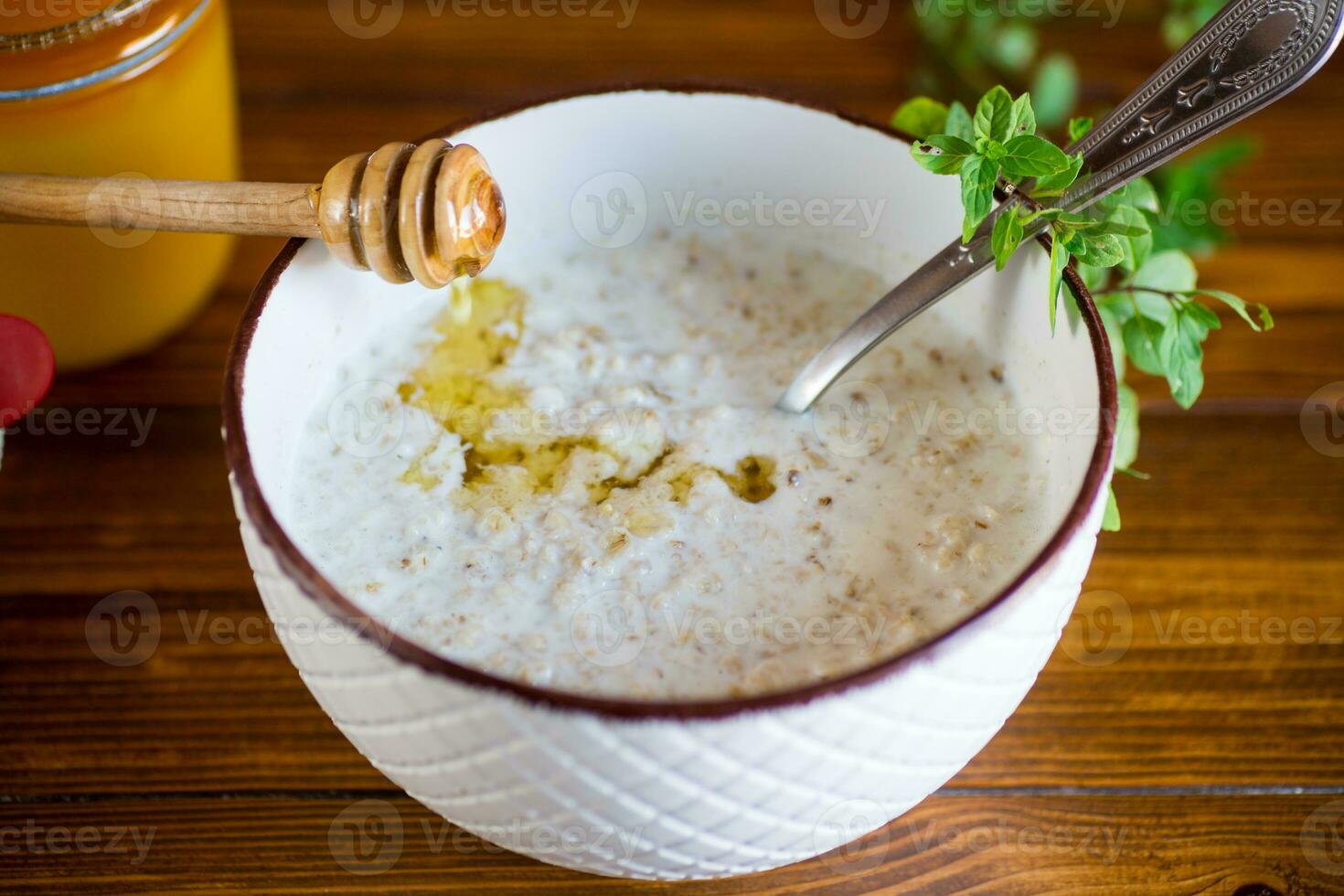 Milch Haferflocken Haferbrei mit Honig zum Frühstück im ein Schüssel hölzern Tisch. foto