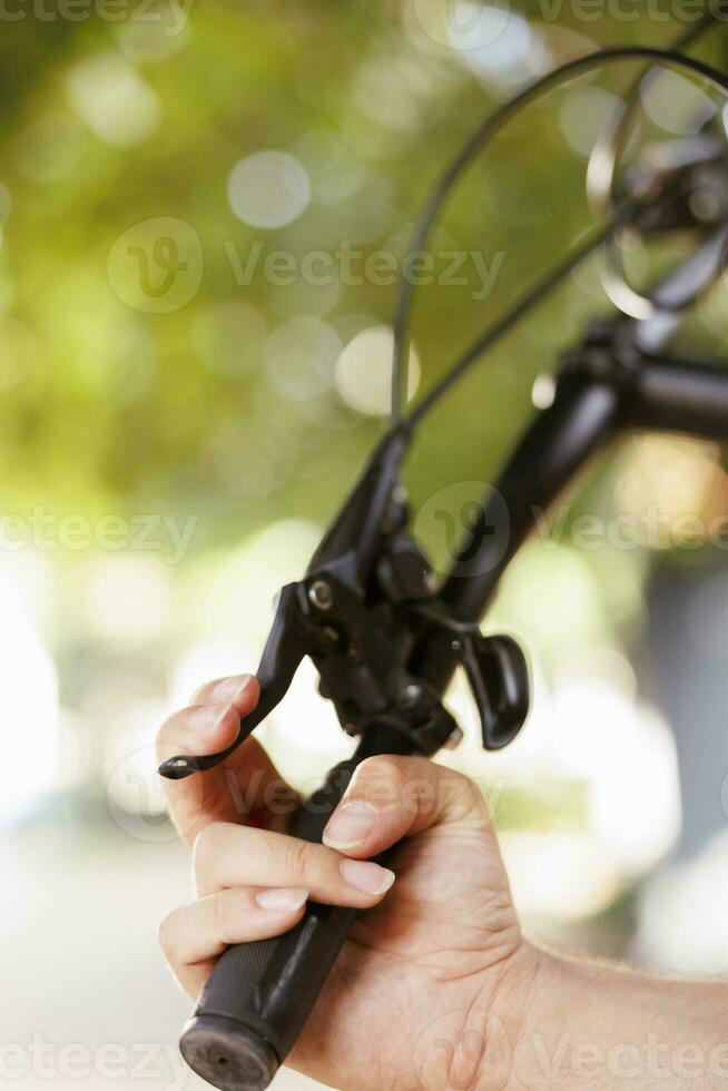 Nahansicht Aussicht von Hand umklammern Fahrrad Bremse Hebel draussen während zusätzlich Wartung. detailliert Bild von kaukasisch Mann reparieren das Schalthebel auf Fahrrad im Vorbereitung zum jährlich Sommer- Freizeit Radfahren foto