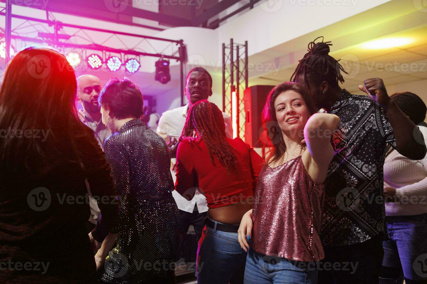 gemischtrassig Paar Tanzen zusammen während Party machen im überfüllt Nachtclub. Mann und Frau Clubbing und haben Spaß auf Tanzfläche beleuchtet mit Scheinwerfer beim Verein Diskothek foto