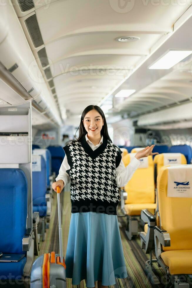 attraktiv asiatisch weiblich Passagier von Flugzeug Sitzung im komfortabel Sitz während Arbeiten Laptop und Tablette mit spotten oben Bereich mit kabellos Verbindung. Reise im Stil, Arbeit mit Anmut. foto