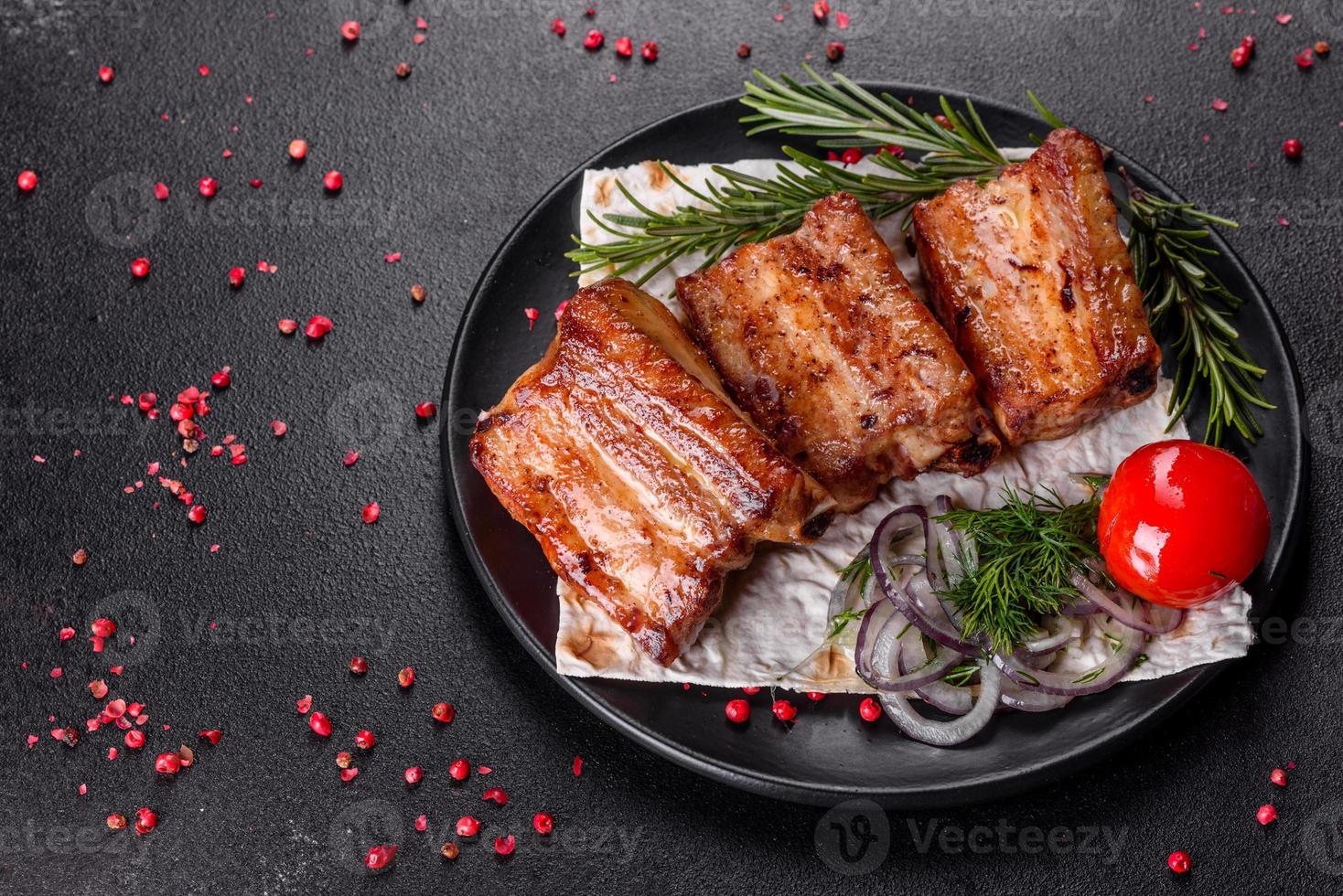 gebratene Rippchen mit Rosmarin, Zwiebeln, Sauce auf Betonuntergrund foto