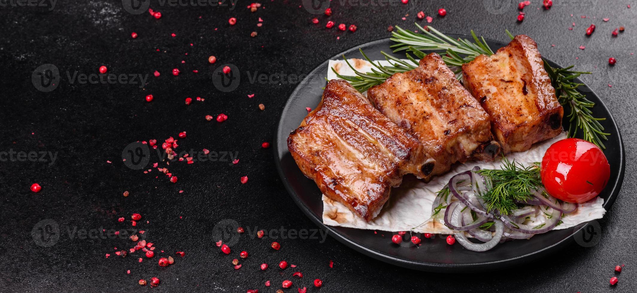 gebratene Rippchen mit Rosmarin, Zwiebeln, Sauce auf Betonuntergrund foto