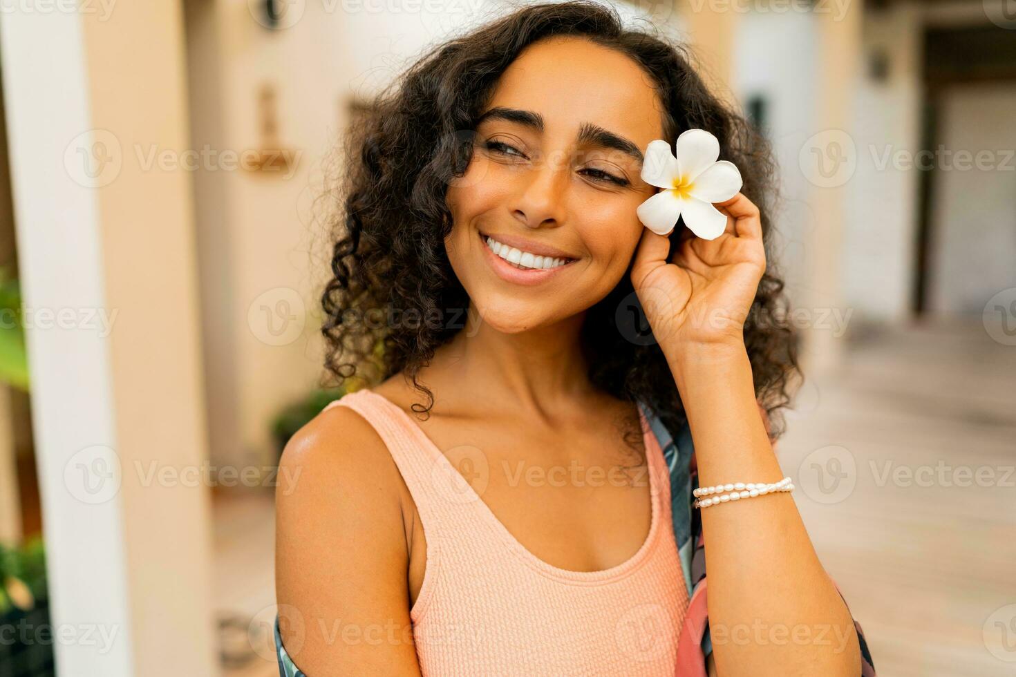 schließen oben Porträt von schön Frau mit tropisch Blume im Hand posieren im Luxus Spa Hotel. Spa und Körper Pflege Konzept. foto