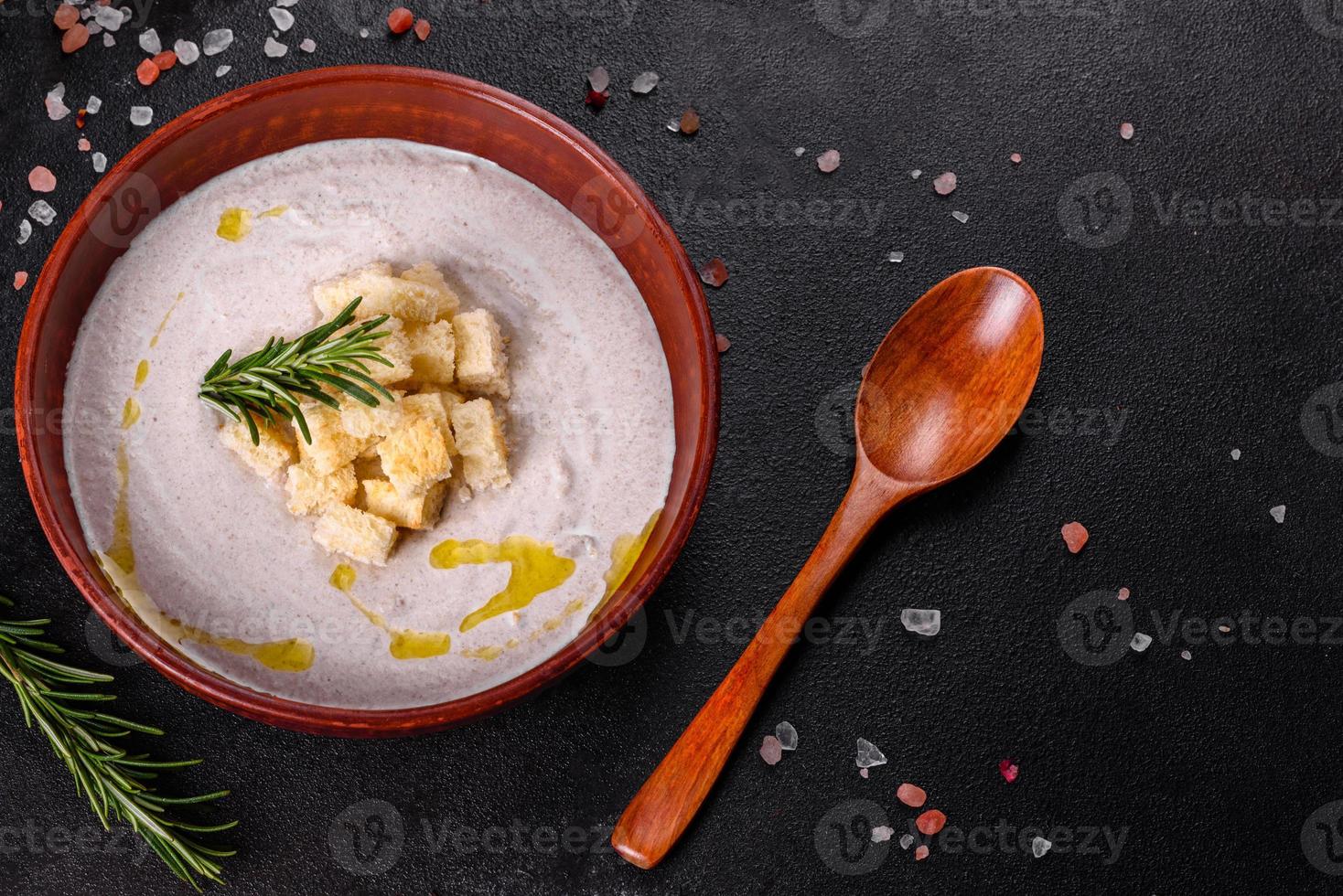 köstliche schöne Pilzsuppe in einem braunen Teller mit einem Holzlöffel foto